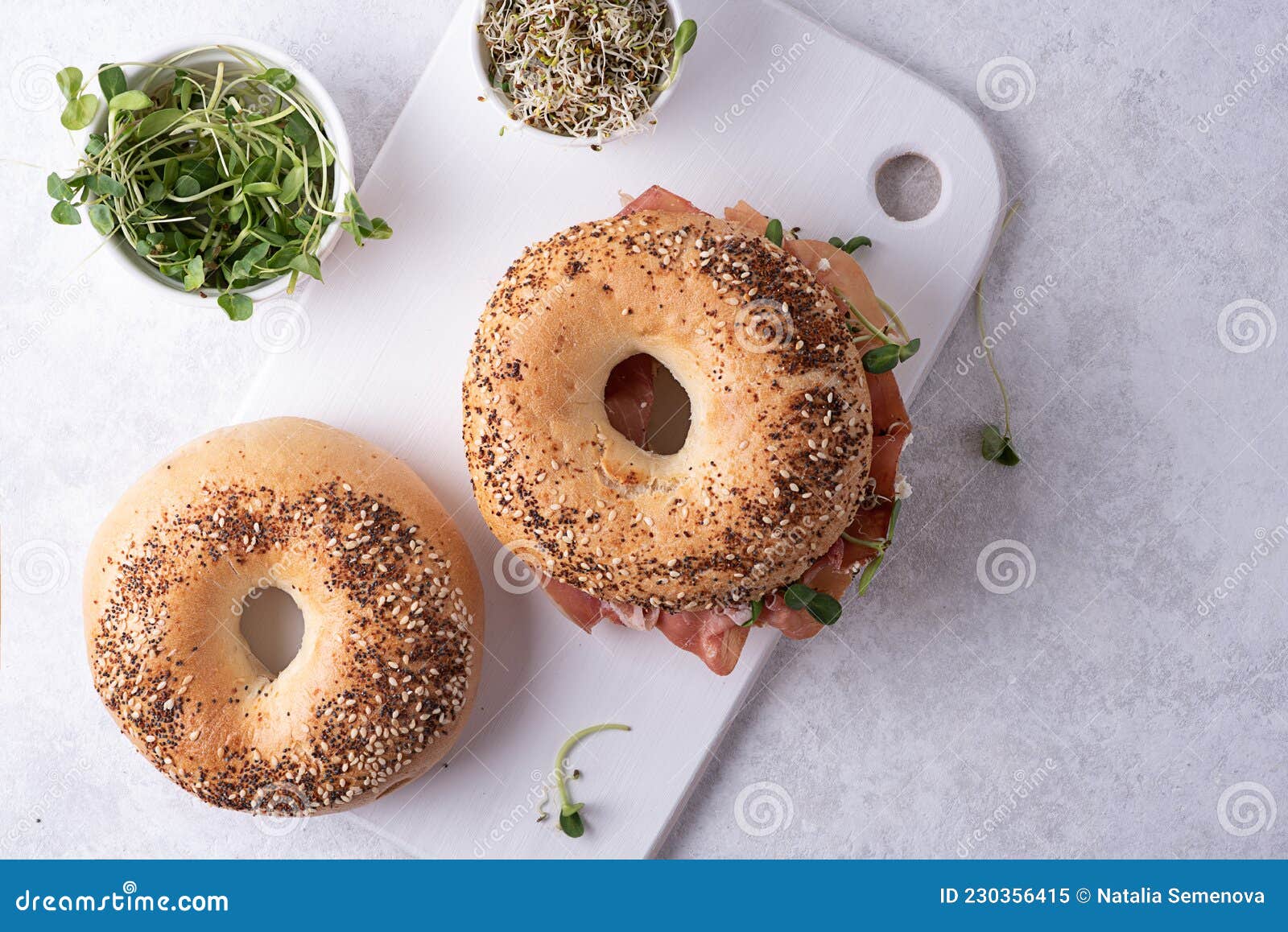 Two Bagels and a Bowl with Microgreens on a Cutting Board, Buns on a