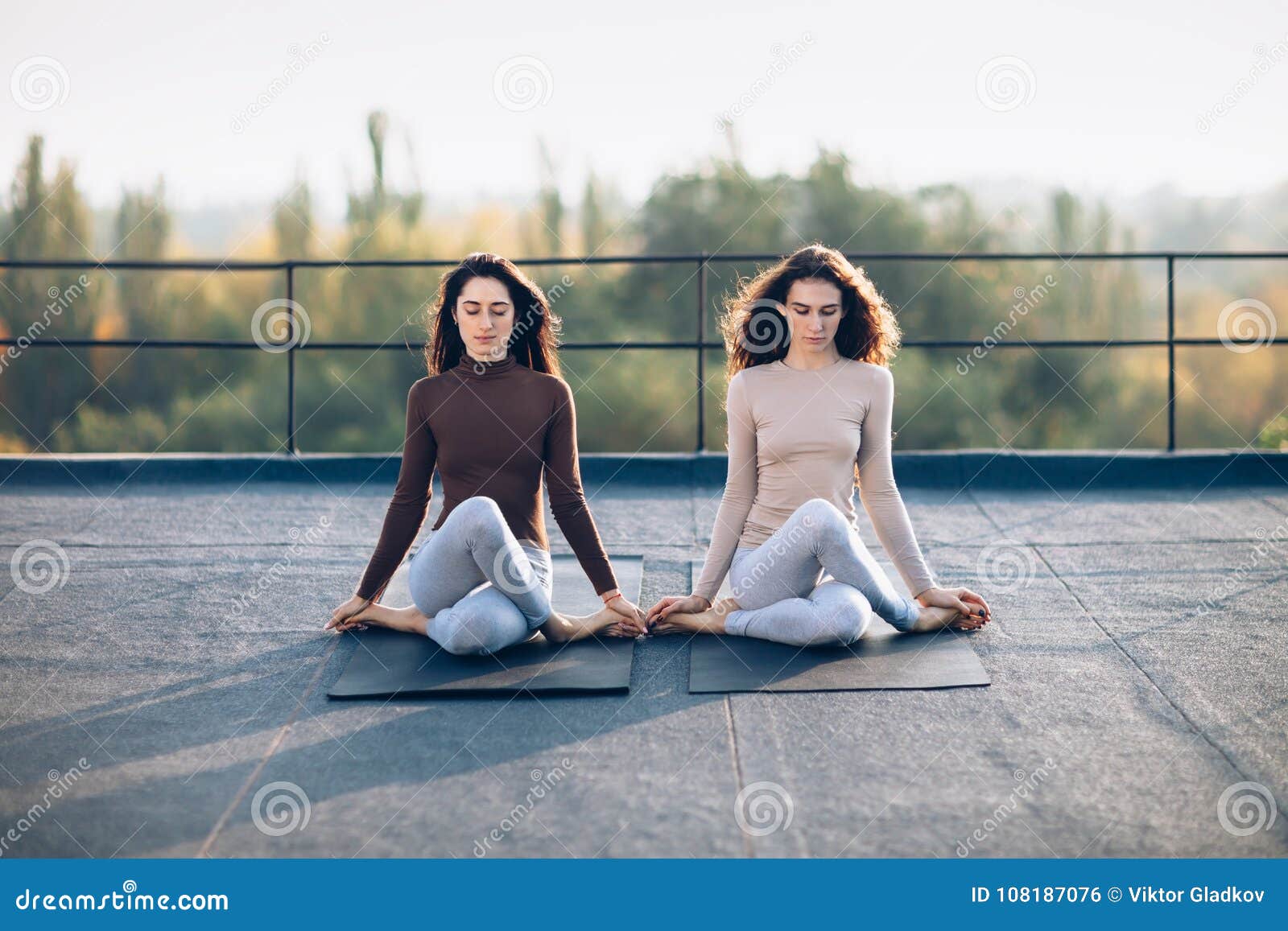 two beautiful women perform meditative pose gomukhasana