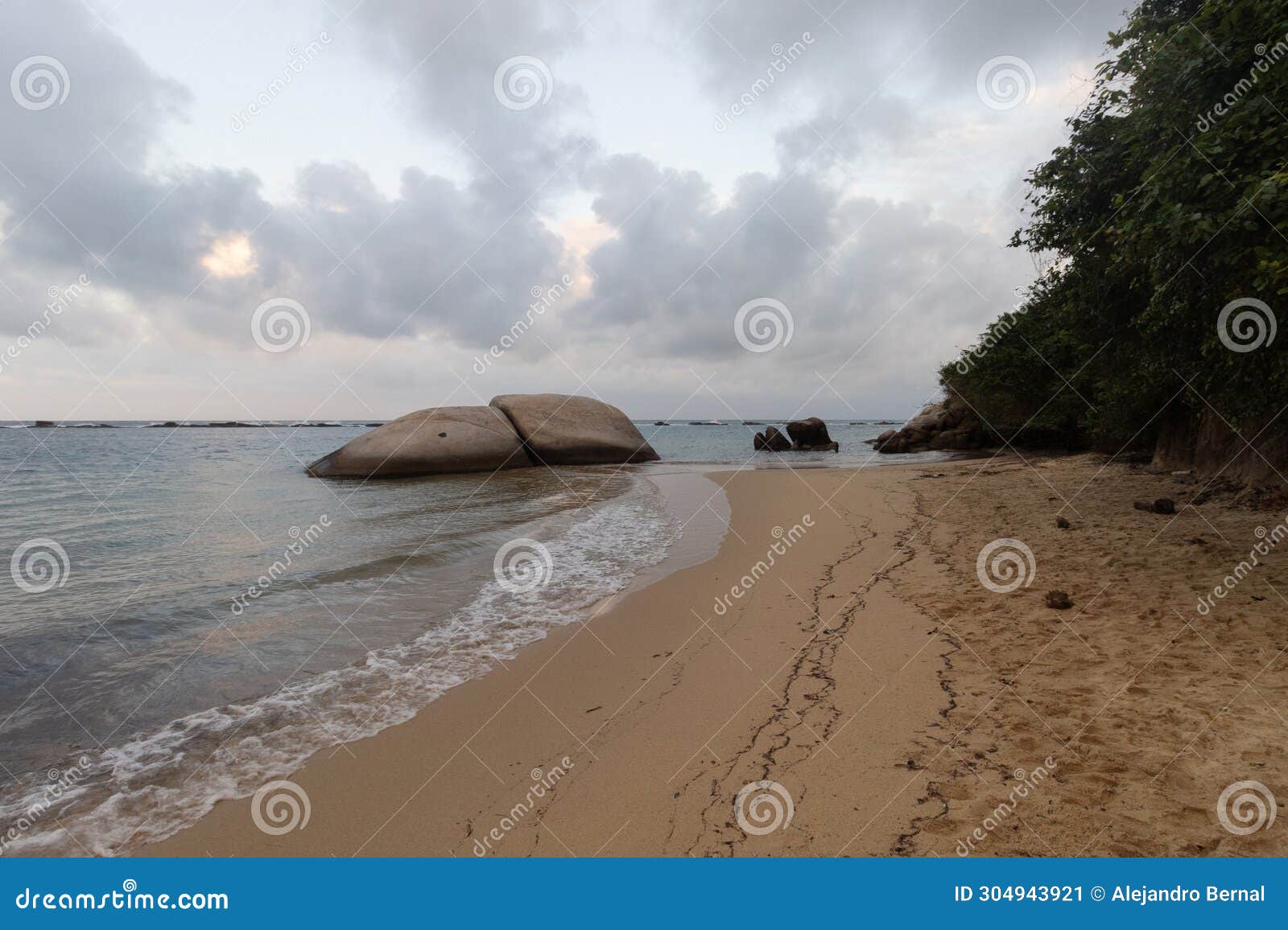 two big rocks in la piscina beach located into tayrona park with orange sunset