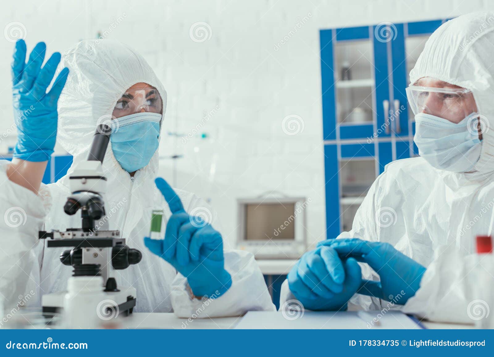 two biochemists in hazmat suits talking in laboratory