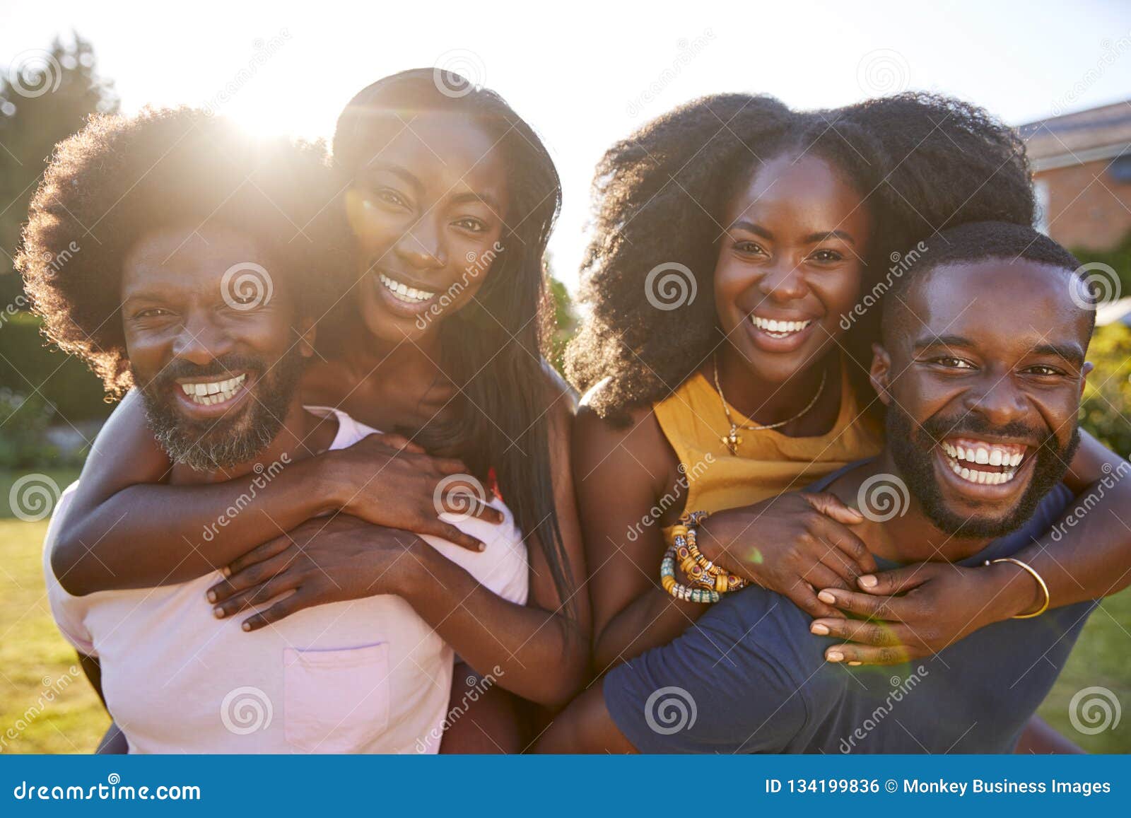 two black couples, men piggybacking their partners, close up
