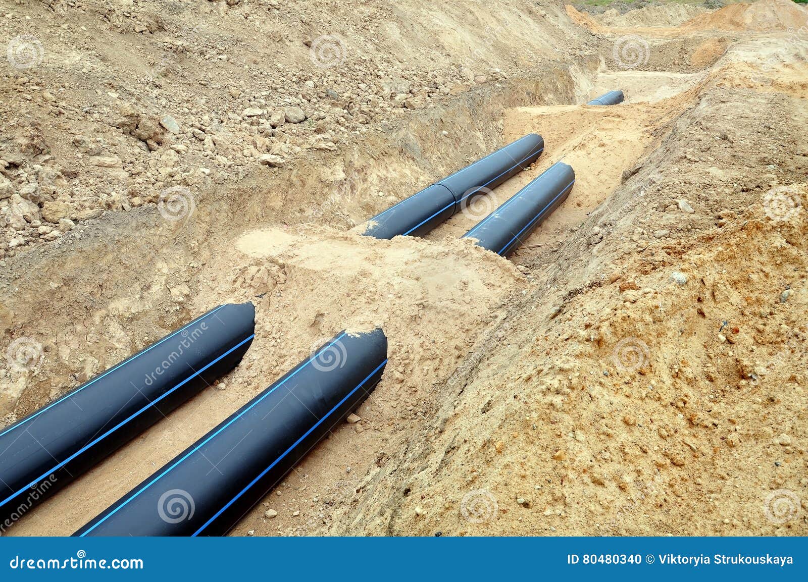 Two Black Plastic Pipes are in a Trench of Sand. Stock Photo Image of