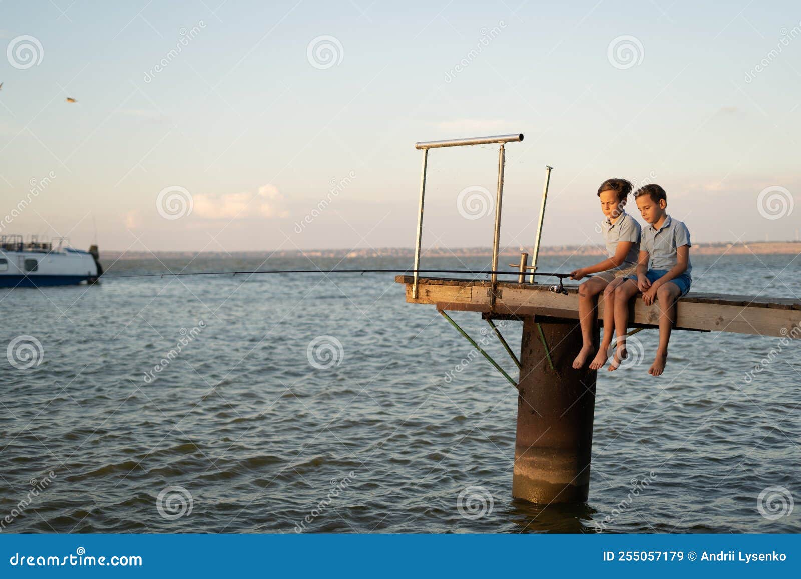 Two Boys Fishing with a Fishing Rod on a Lake at Sunset. Children