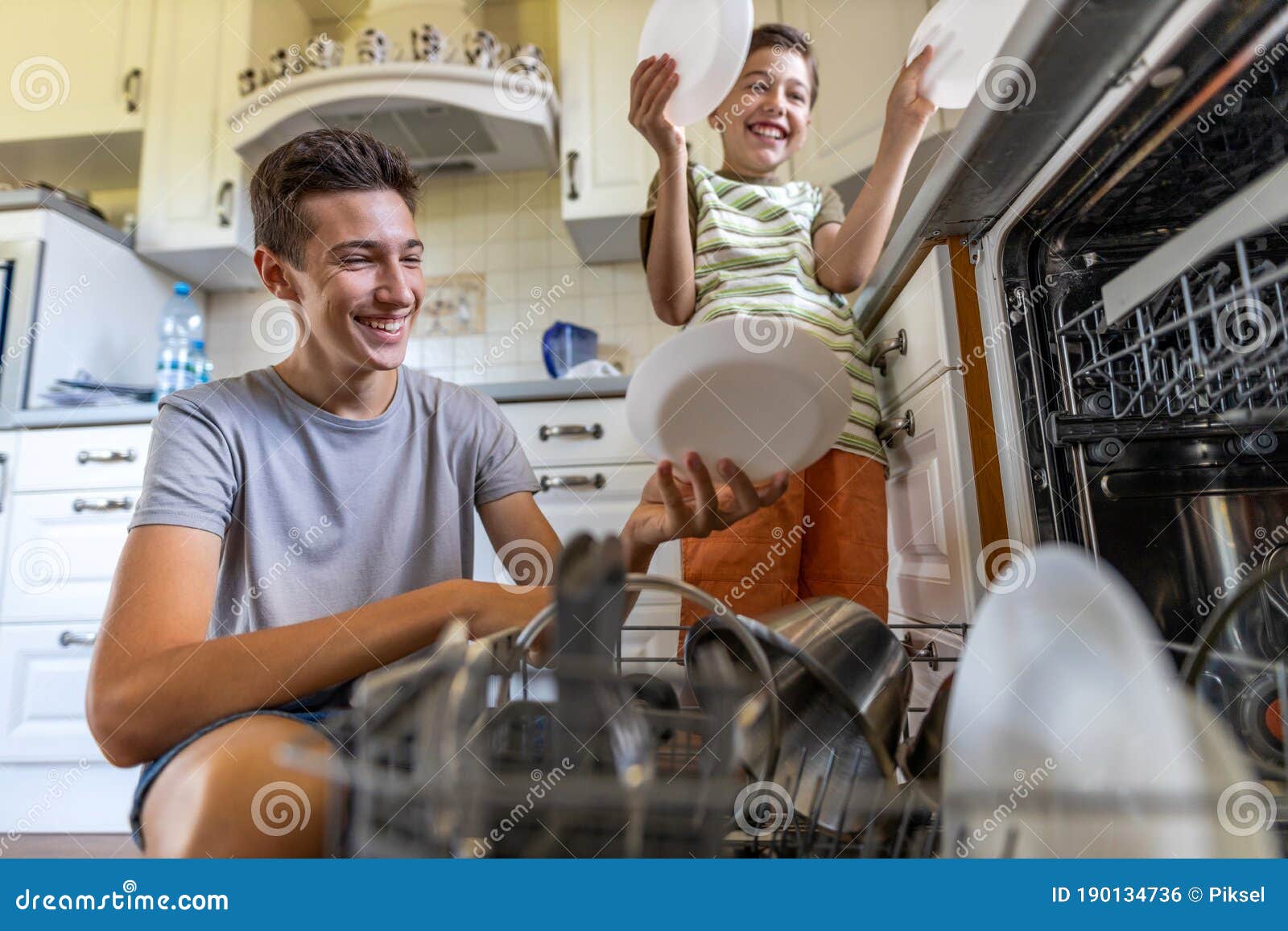 two boys loading the dishwasher together