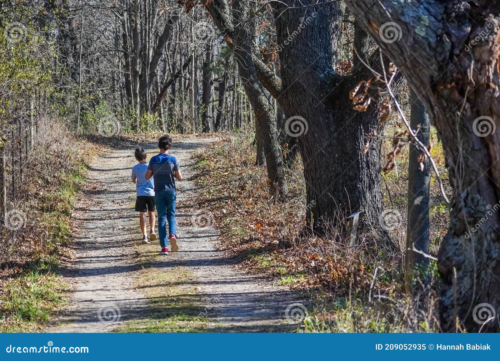 two boys walking on a path in woods