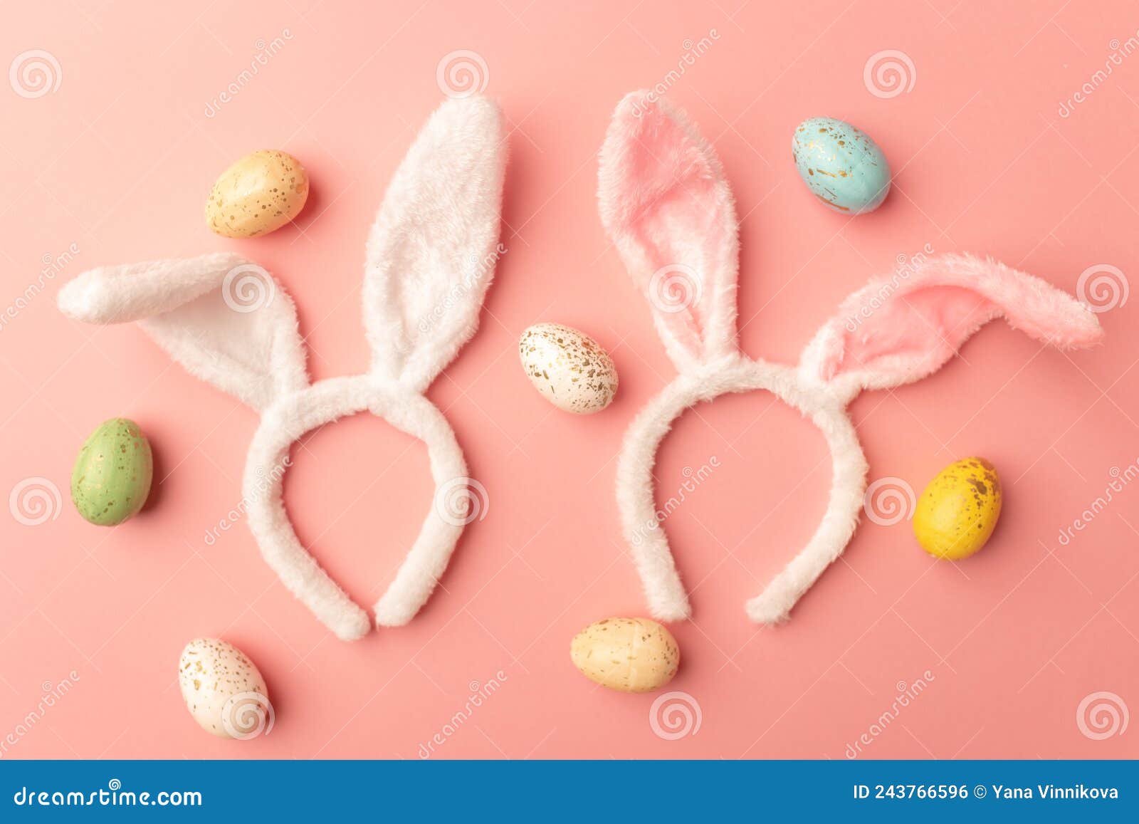 Two Bunny Ears and Bright Easter Eggs on a Pink Background, Top View