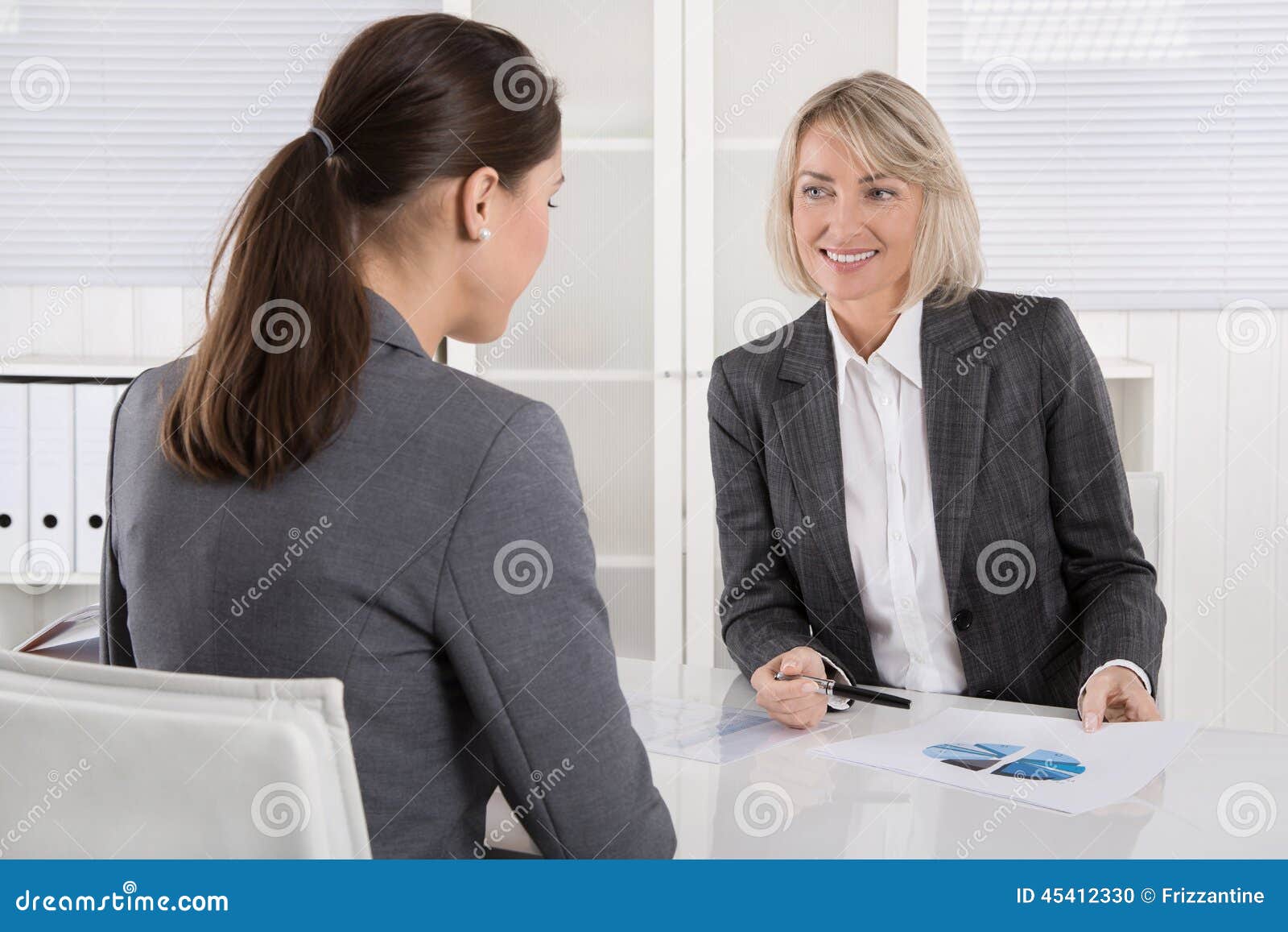 two business woman sitting at desk: customer and adviser talking