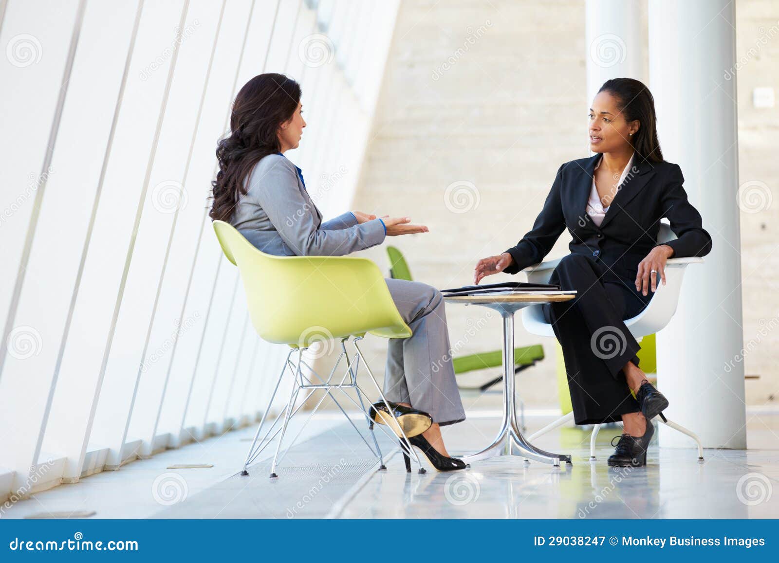 two businesswomen meeting around table in modern office