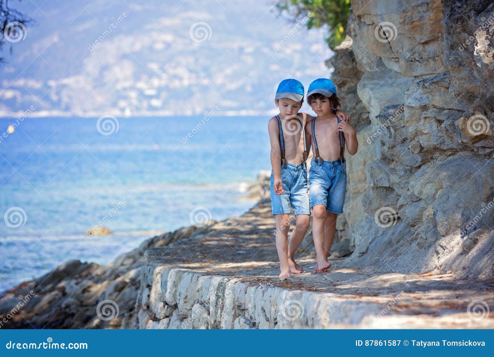 two children, boy brothers, walking on a path around mediterranian sea on french riviera