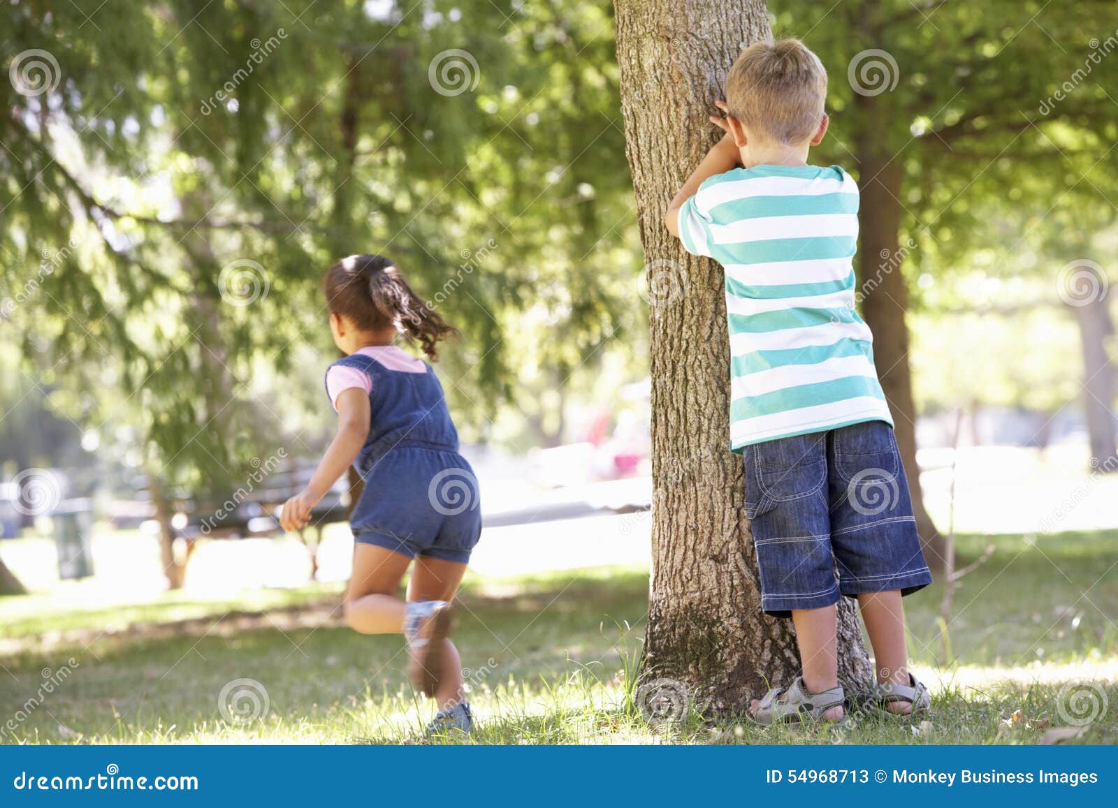 two children playing hide and seek in park