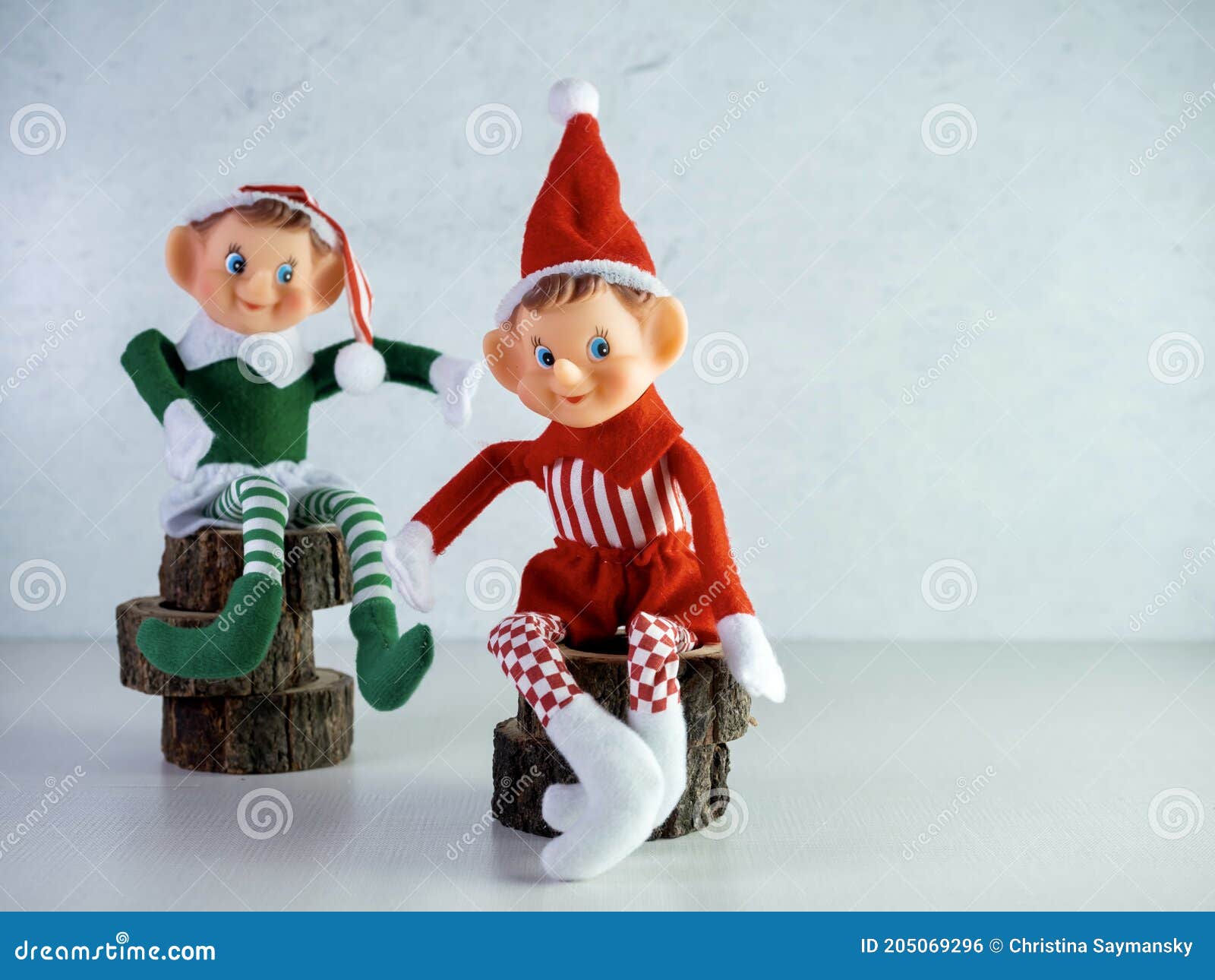 Two Christmas Elves Sitting on Wooden Tree Trunks Pieces, One with a ...