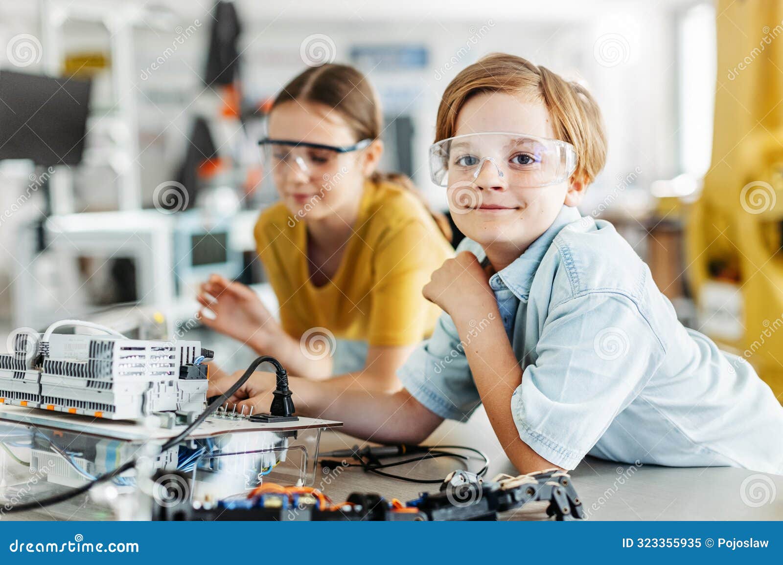 two classmates working togeter on circuit board, building robot in after-school robotics club. children learning