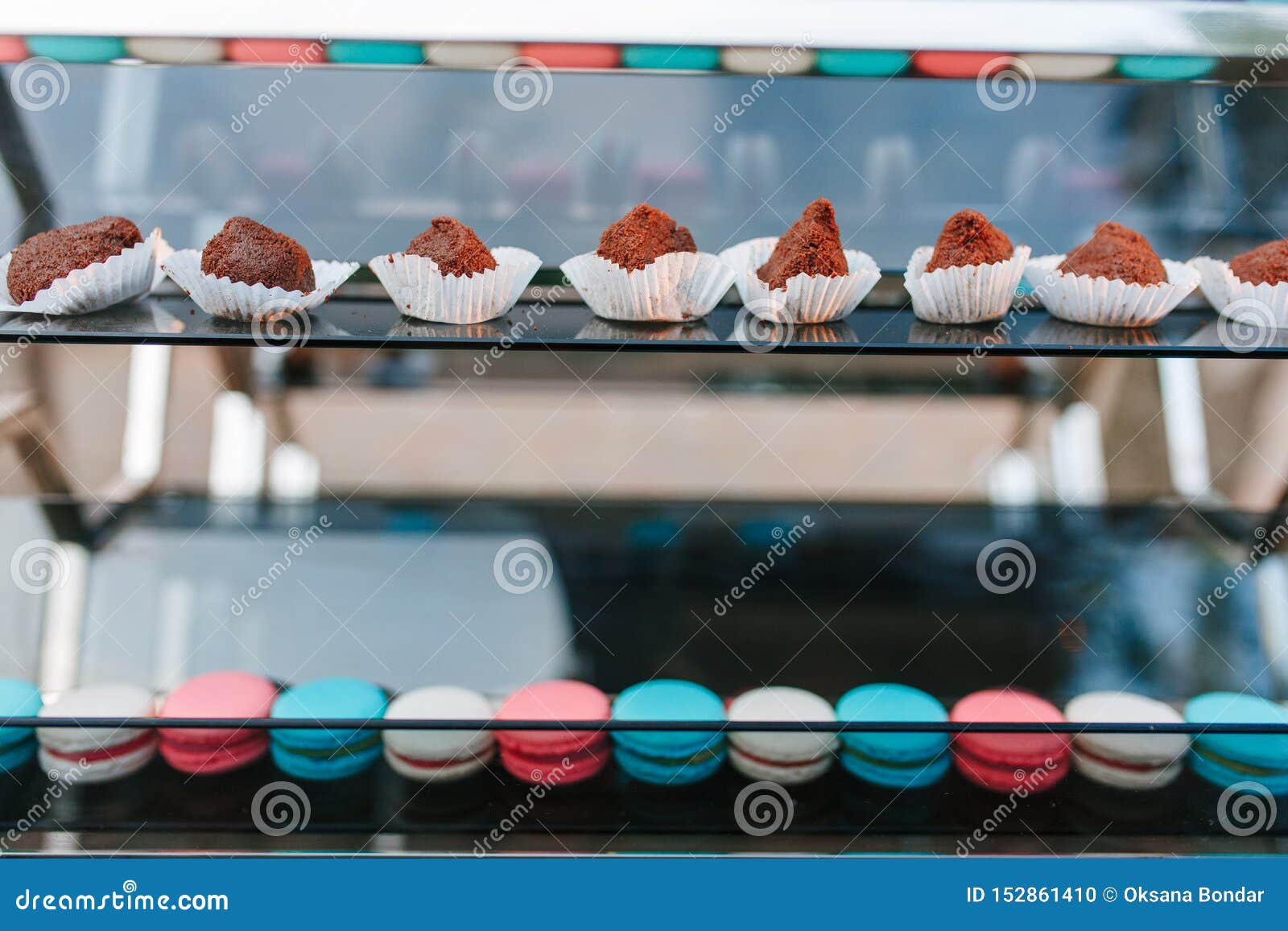 two color macaroons and chocolate cakes on glass display shelves