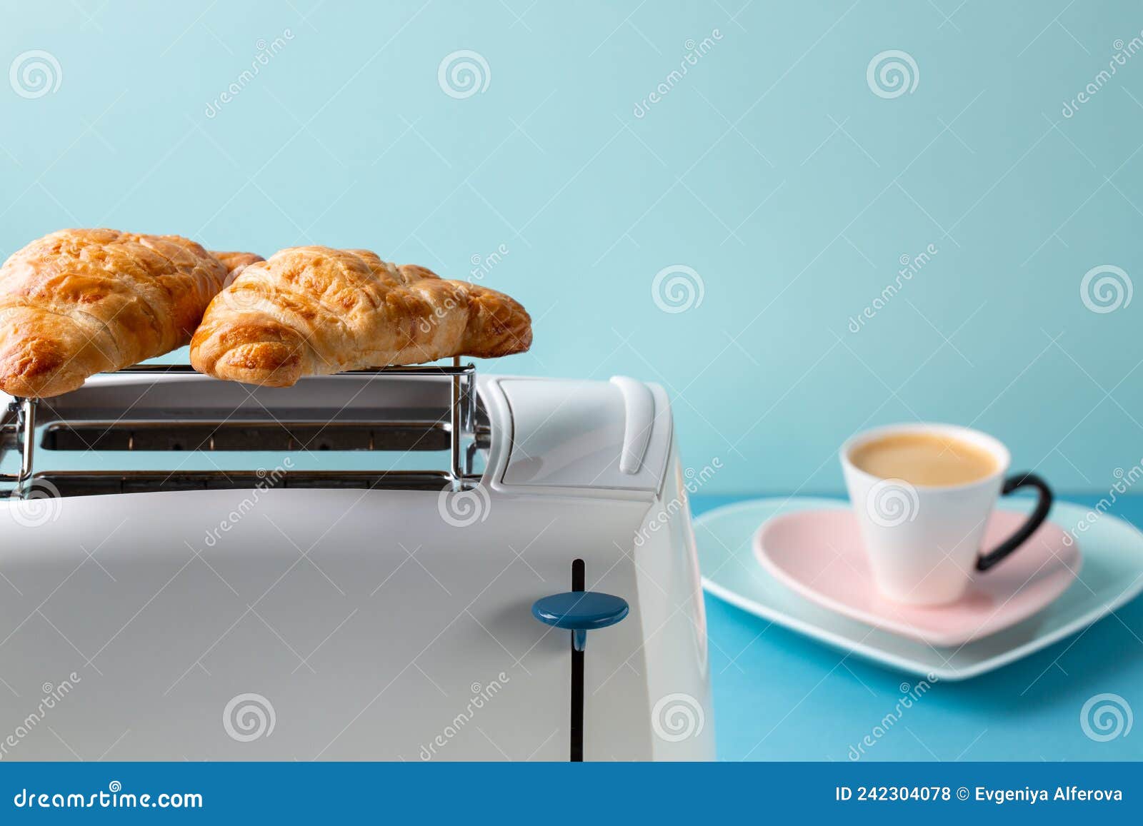 Two Croissants are Warmed Up on Toaster on Blue Background. Copy Space