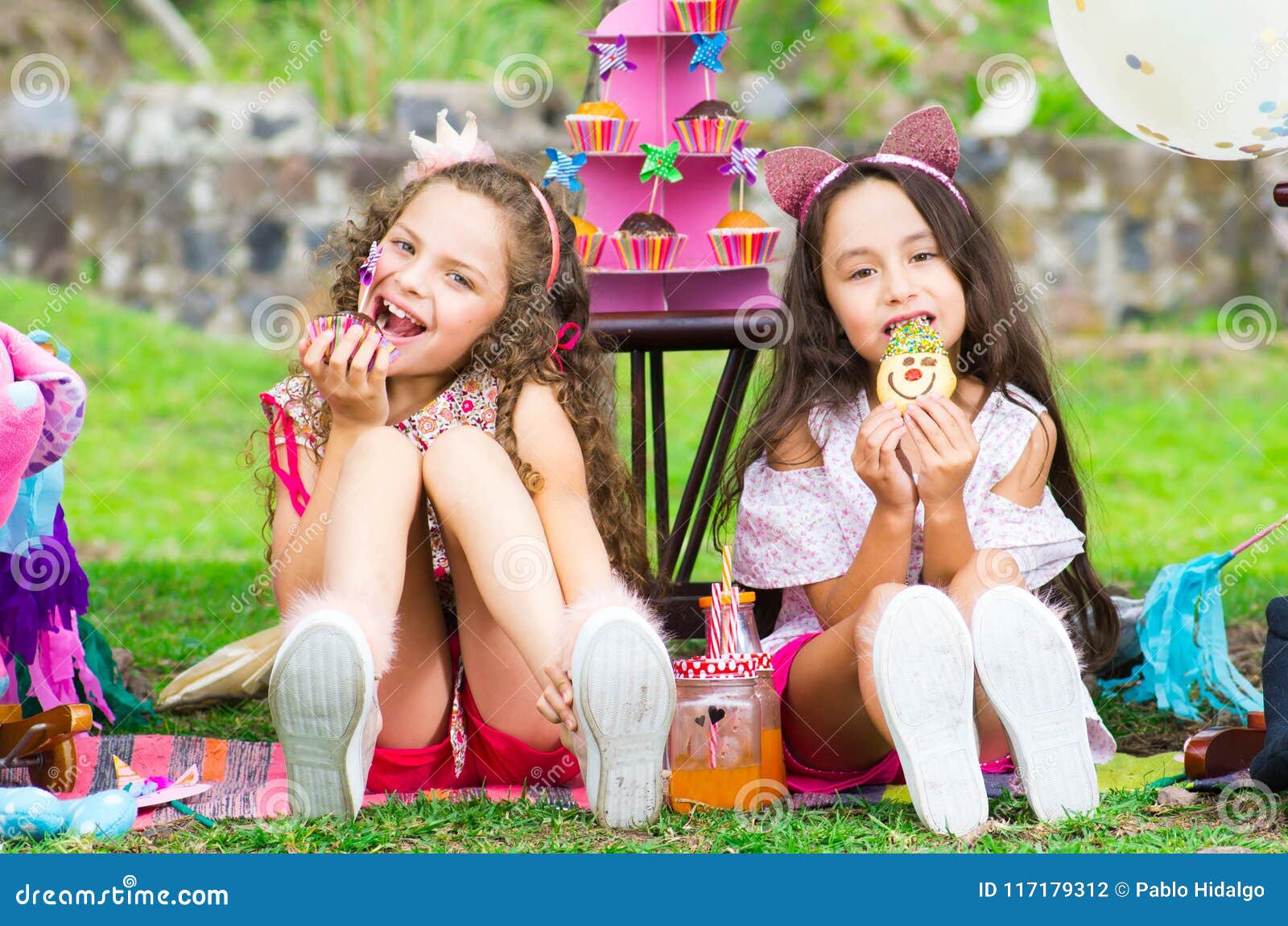 Two Cute Little Sisters In The Garden Curly Girl Eating A Cupcake And