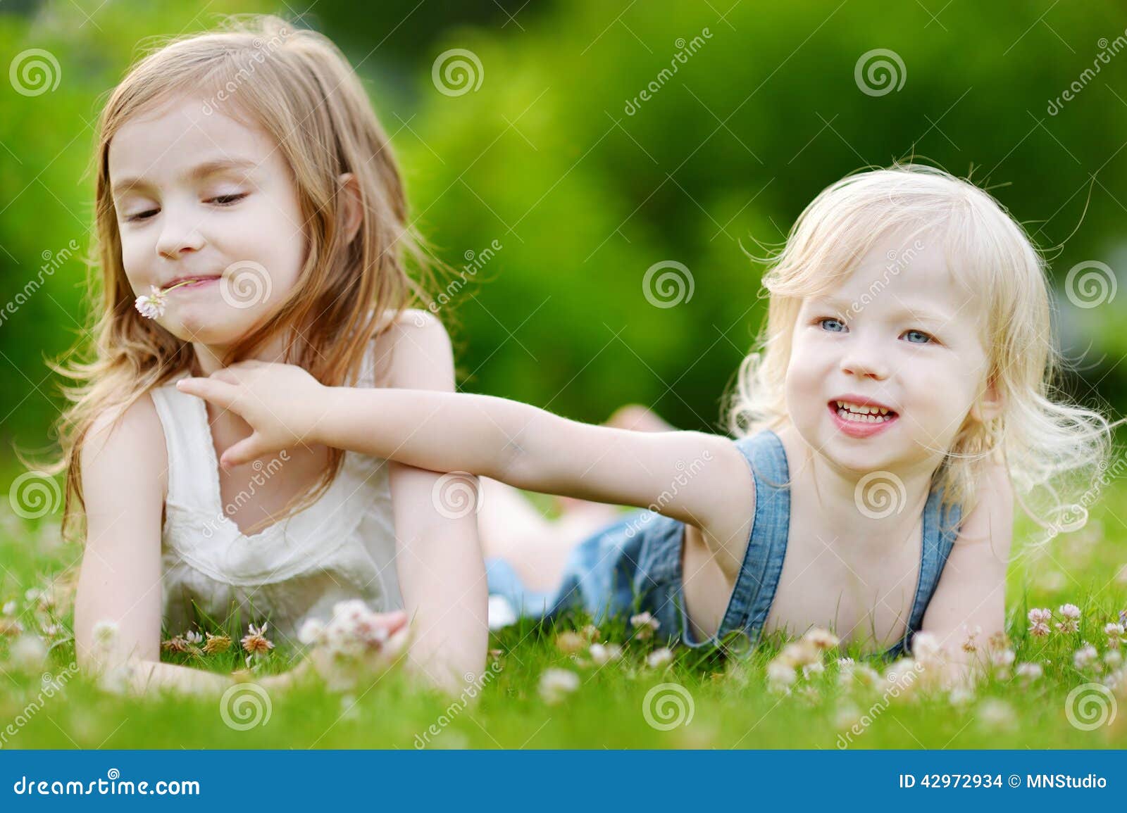 Two Cute Little Sisters Laying in the Grass Stock Photo - Image of ...