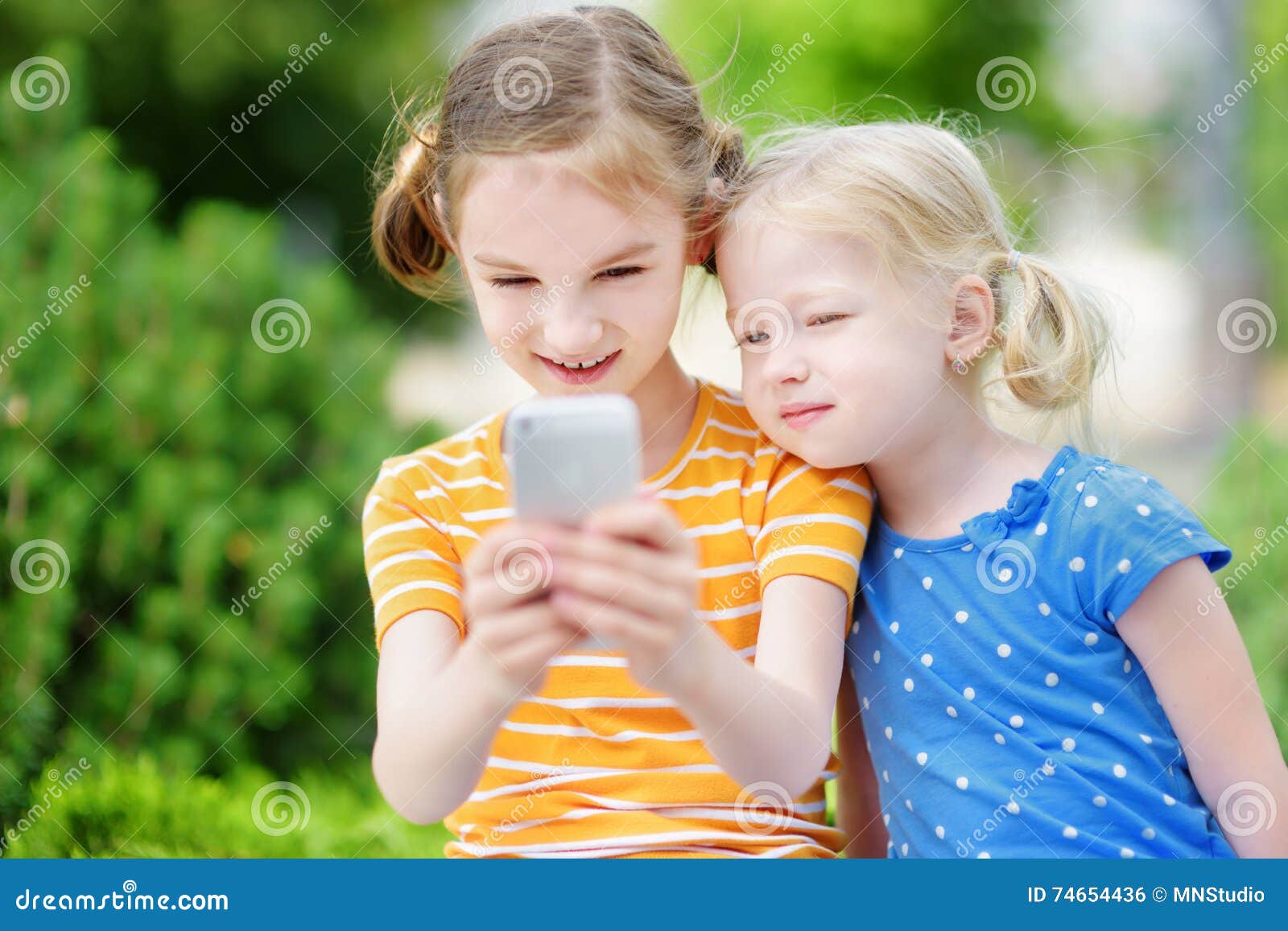 Two Cute Little Sisters Playing Outdoor Mobile Game on Their Smart ...