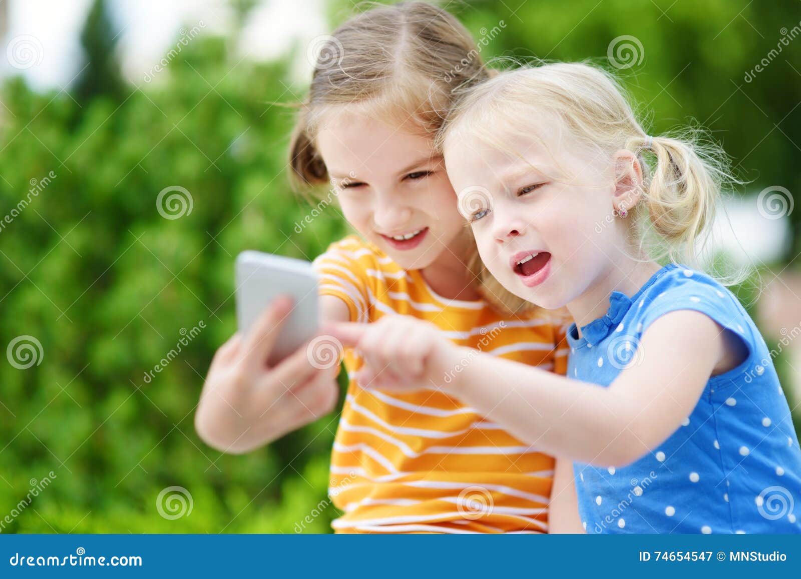 Two Cute Little Sisters Playing Outdoor Mobile Game on Their Smart ...