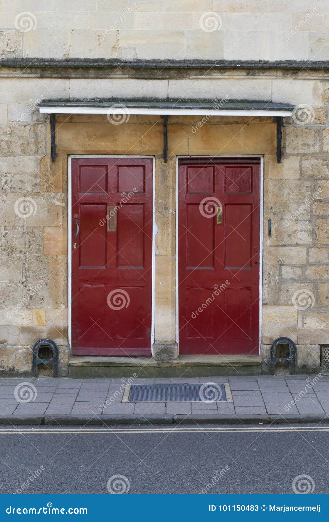 Two Dark Red Front Doors On The Stone Wall Stock Image