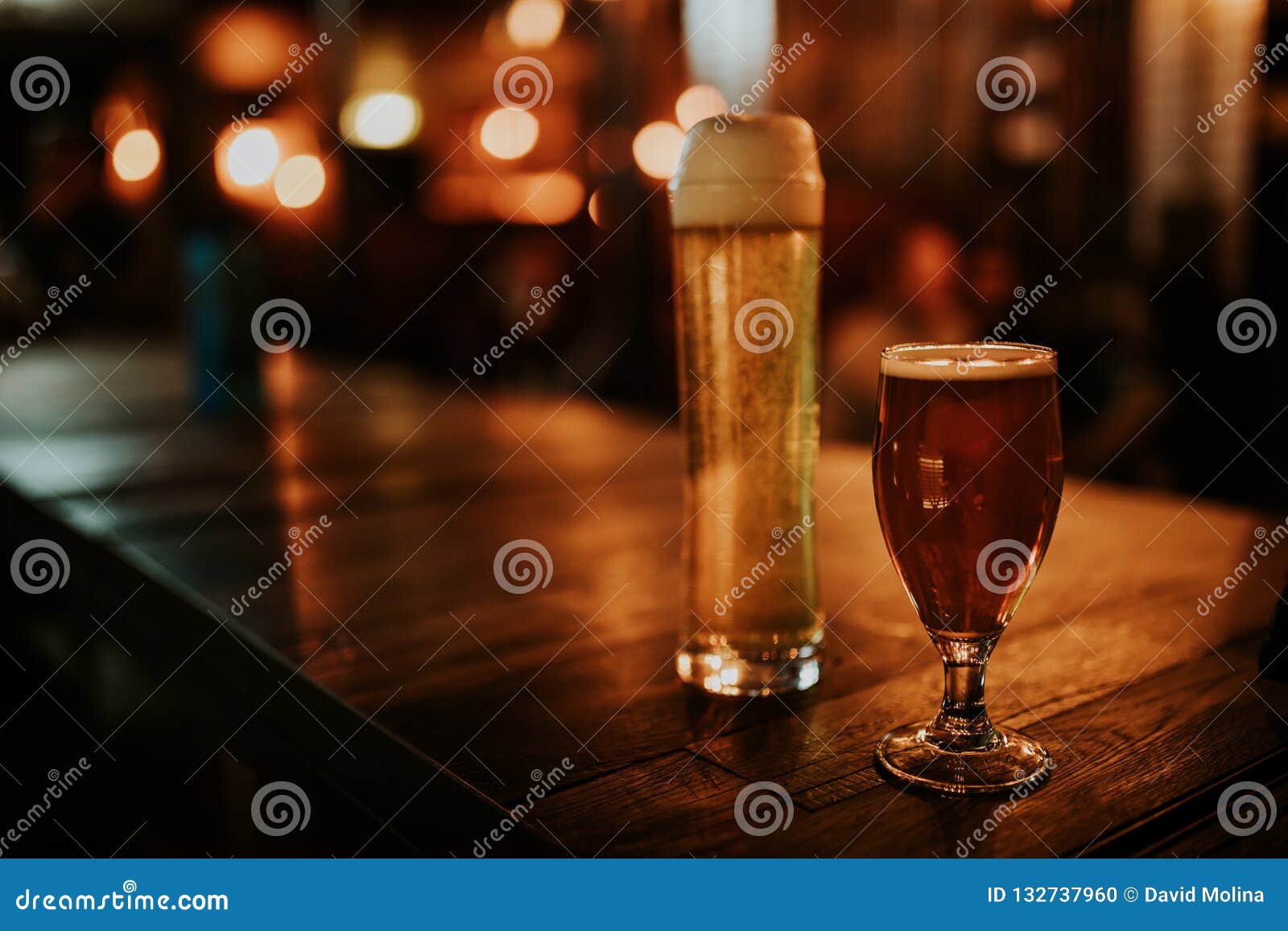 Two Different Beers on a Wooden Table, with Pub Lights in the Background at Night Stock Photo