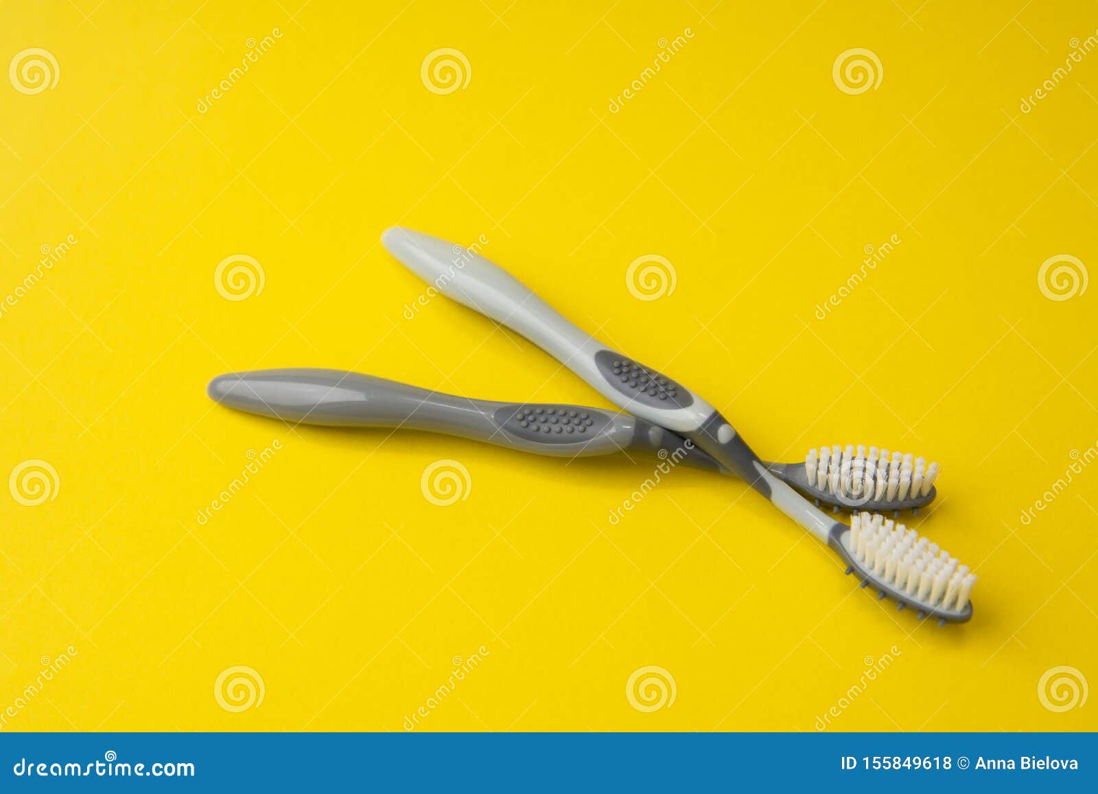 Two Different Grey Toothbrushes on a Yellow Background. Stock Photo