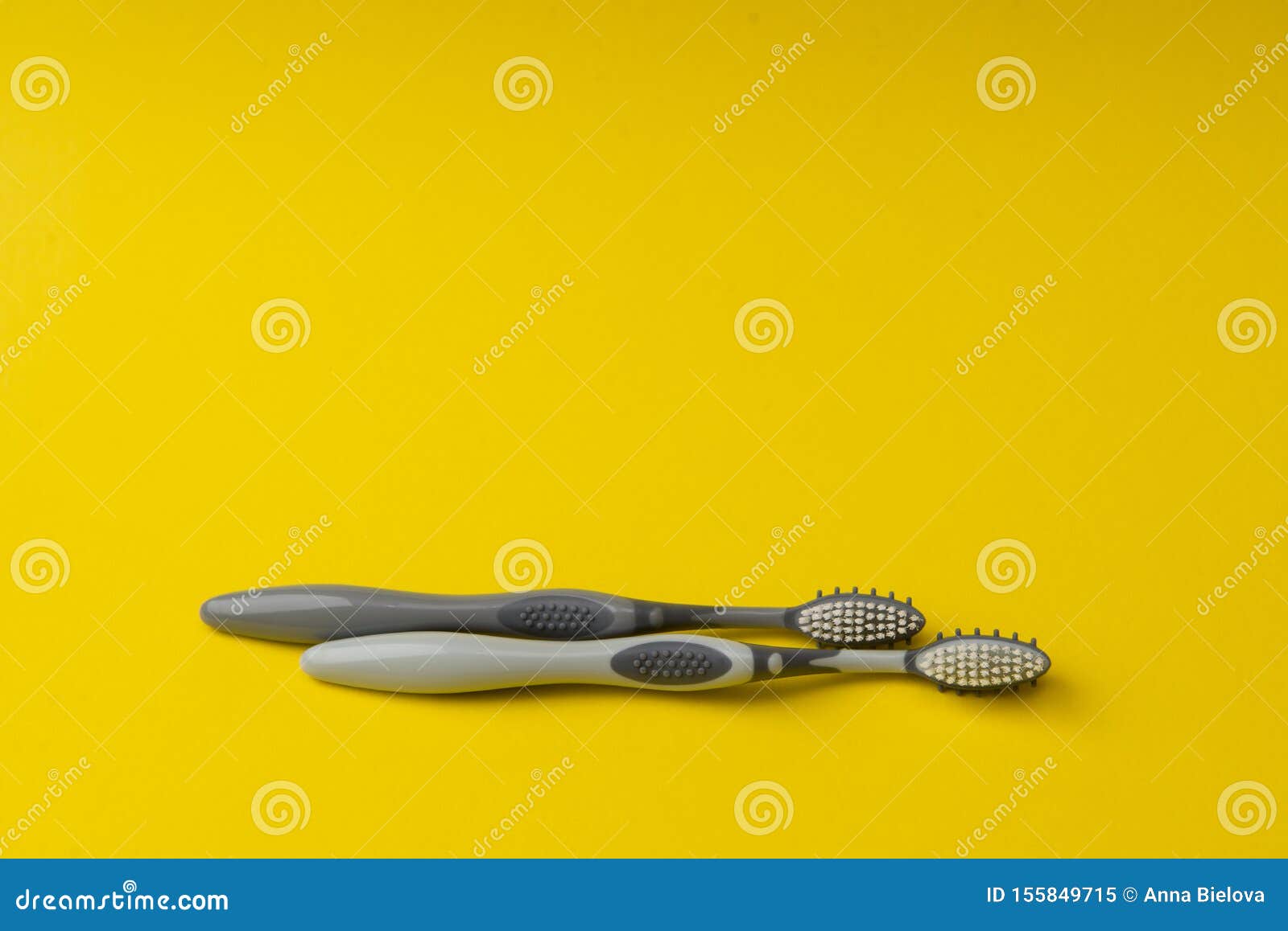 Two Different Grey Toothbrushes on a Yellow Background. Stock Image