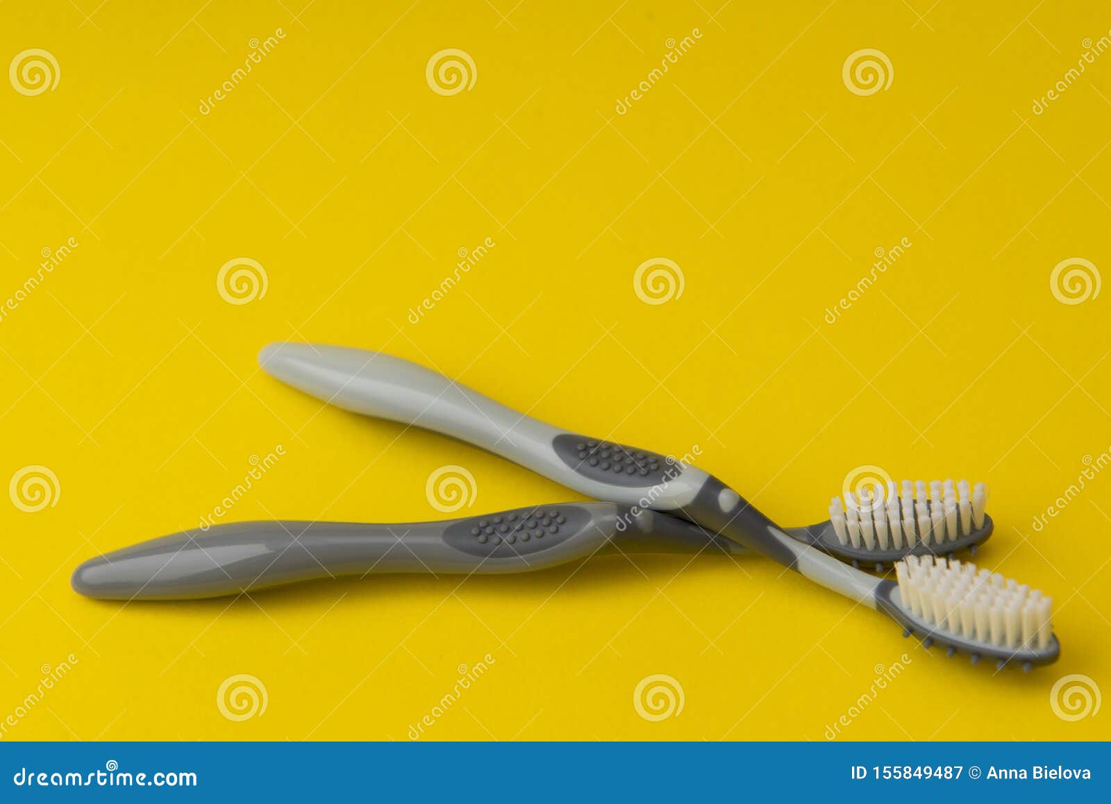 Two Different Grey Toothbrushes on a Yellow Background. Stock Image