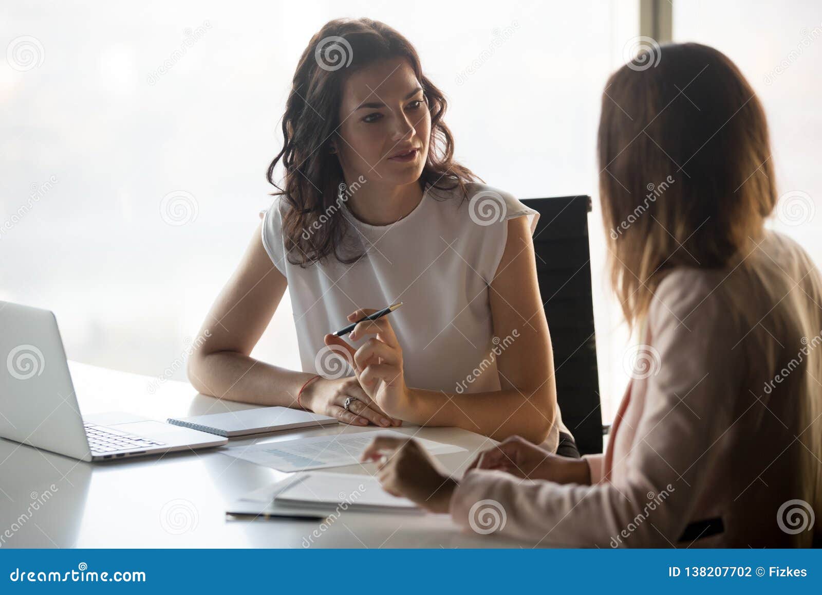 two diverse serious businesswomen talking working together in office