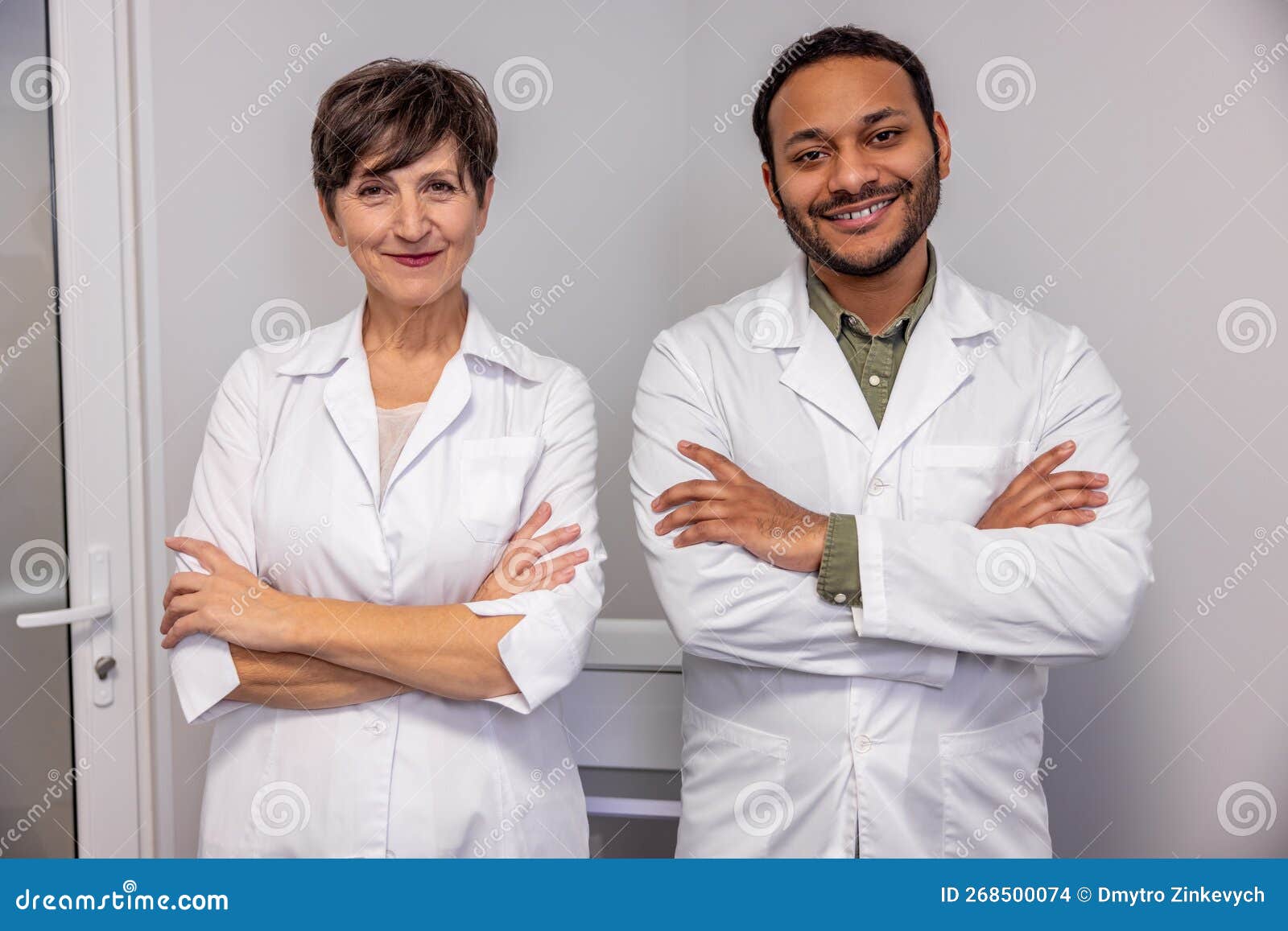 Two Doctors in White Scrubs Standing with Their Arms Crossed Stock