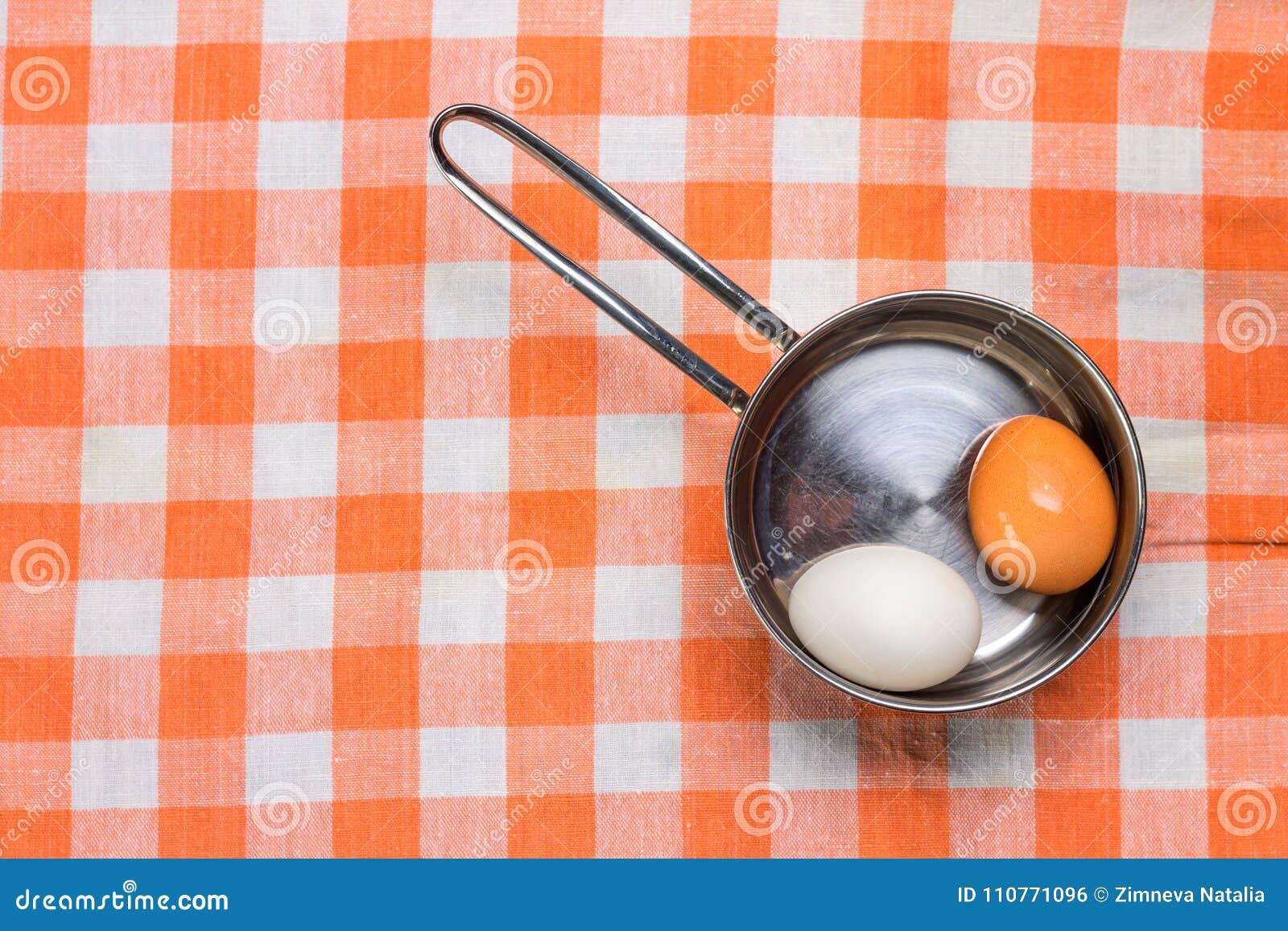 two eggs in saucepan on checered towel