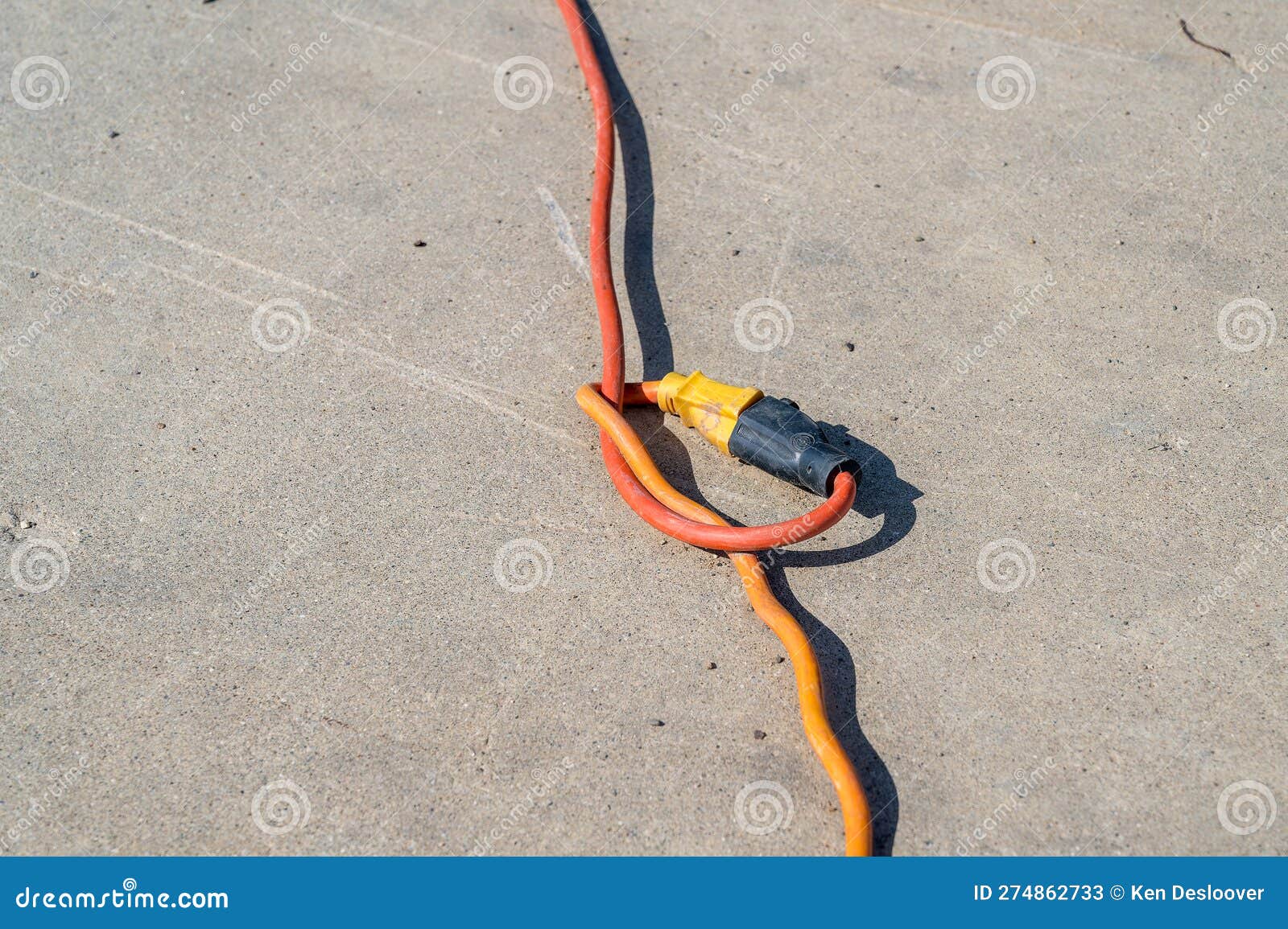 Two Extension Cords Plugged into Each Other with a Knot on a Cement Background Stock Image