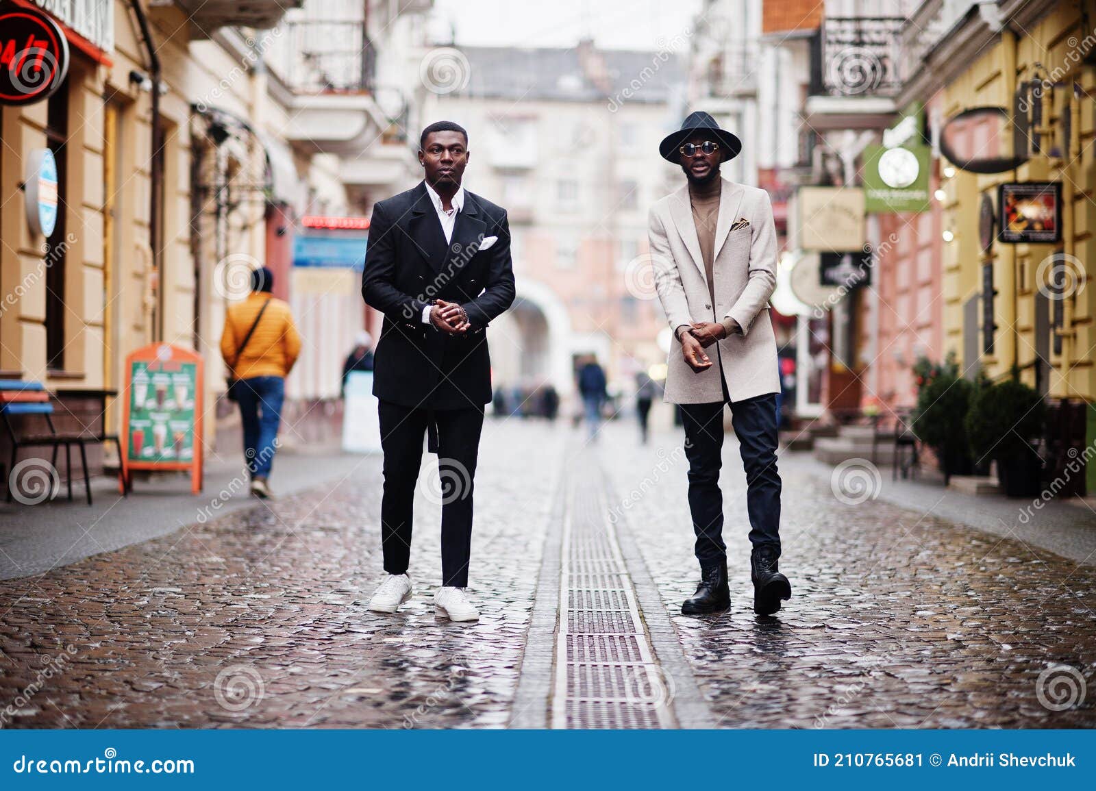 two fashion black men walking on street. fashionable portrait of african american male models. wear suit, coat and hat