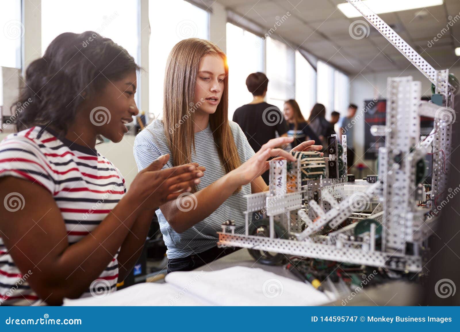 two female college students building machine in science robotics or engineering class