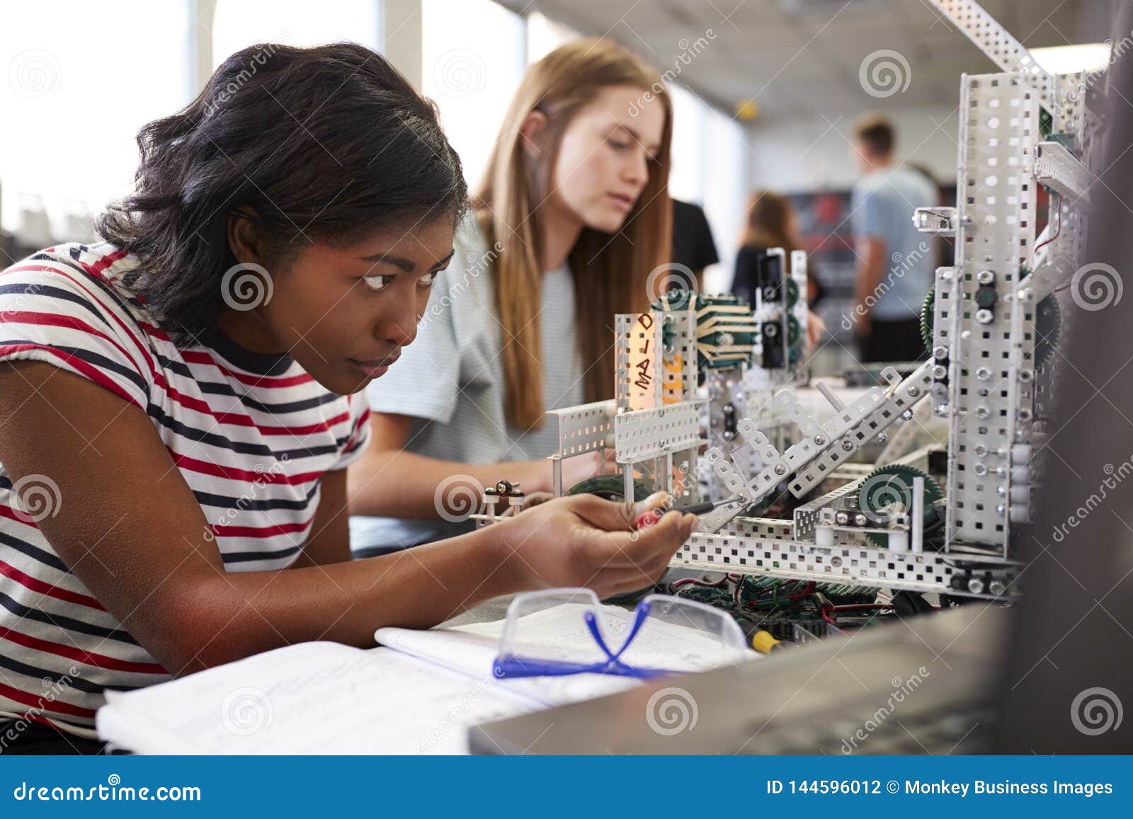 two female college students building machine in science robotics or engineering class