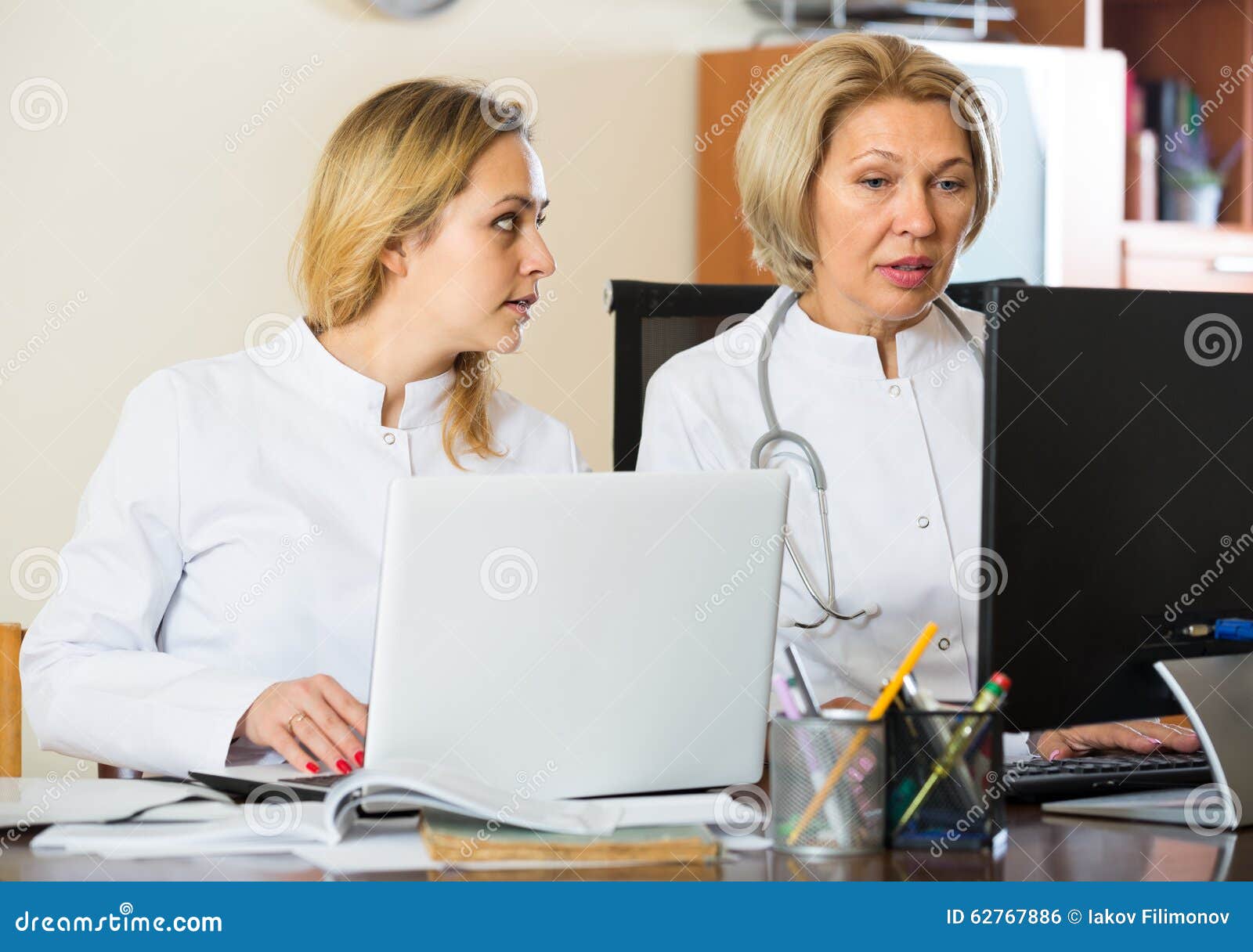 Two female doctors working together. Two female professional doctors with stethoscope working in office together