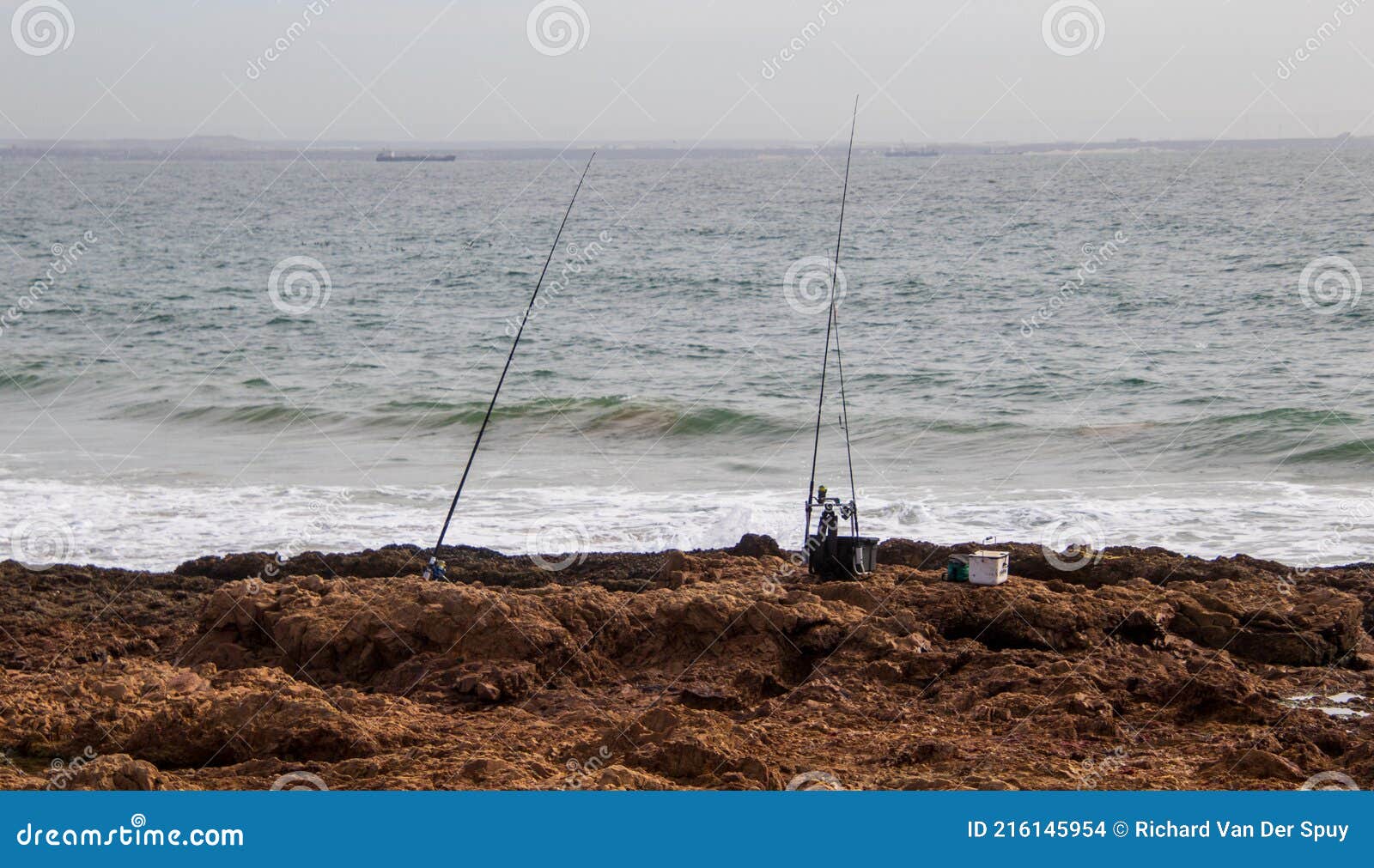 https://thumbs.dreamstime.com/z/two-fishing-poles-next-to-sea-rods-rocks-ocean-used-rock-anglers-216145954.jpg