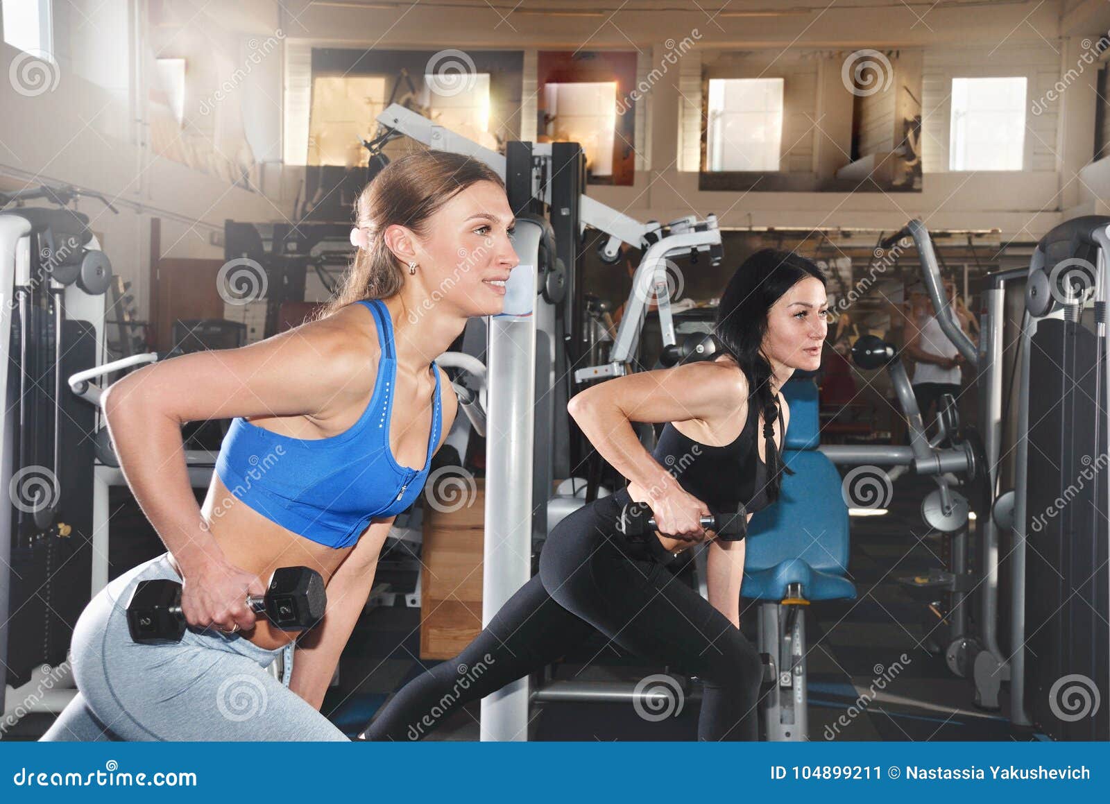 Two Fitness Girls Lifting Dumbbells in the Gym Stock Image - Image of ...