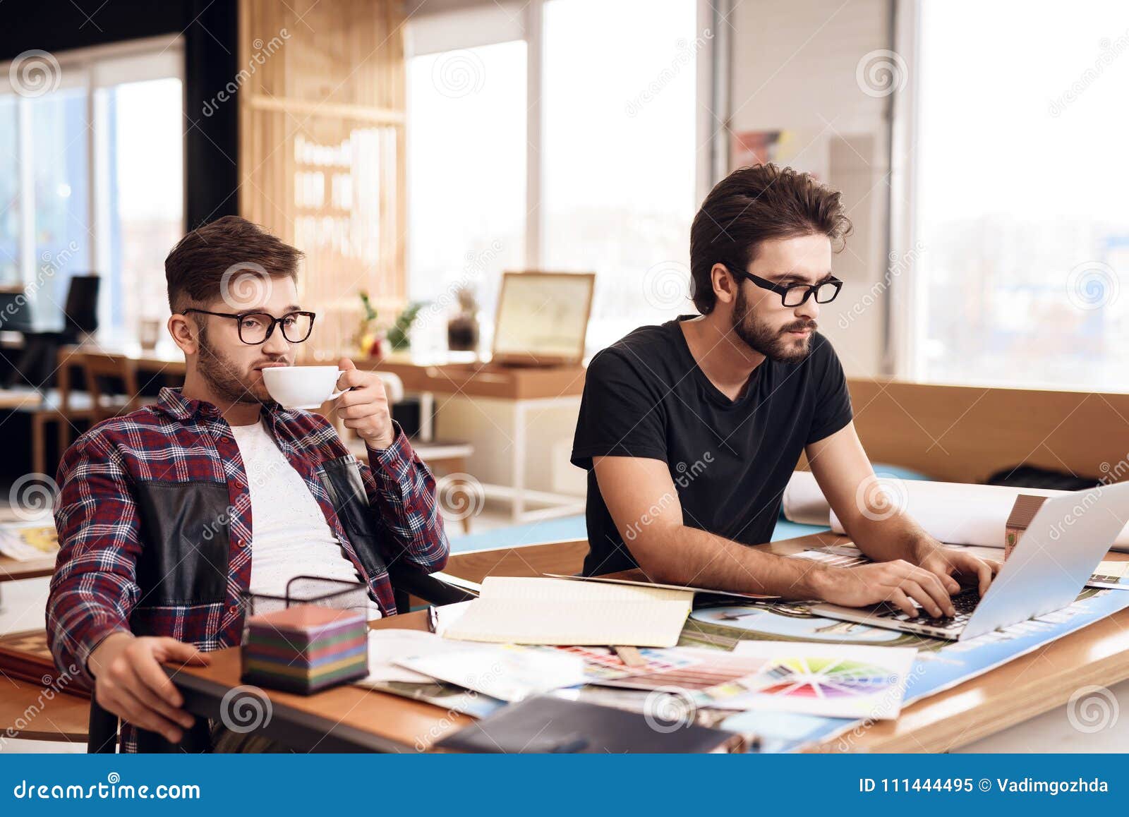 two freelancer men working at laptop and drinking coffee at desk.