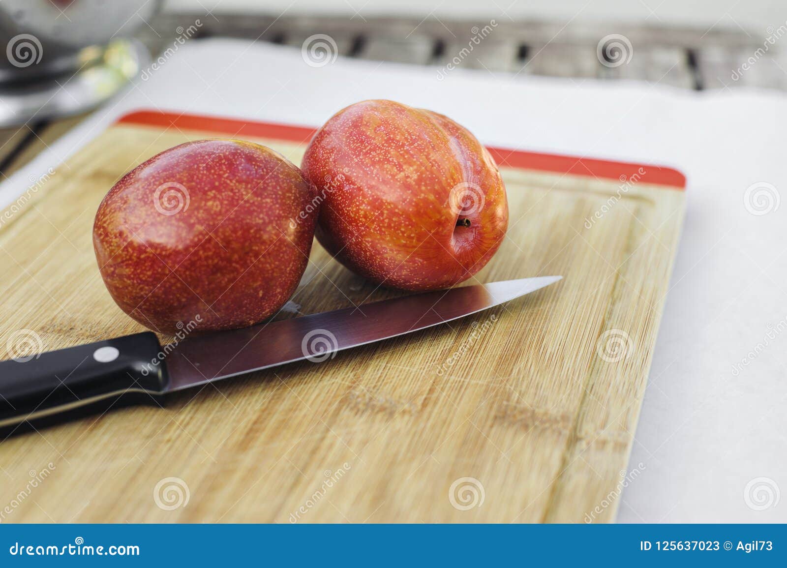 pair of amigo pluots on a wood chopping board with a knife