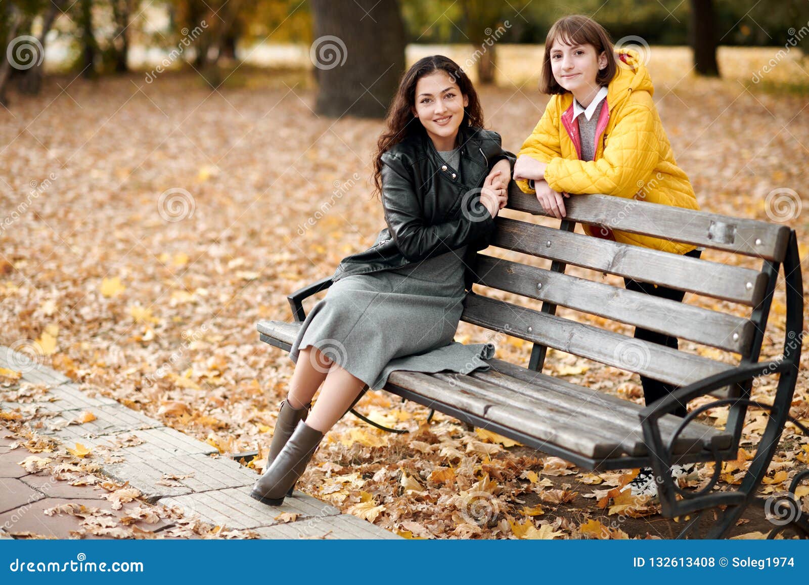 Two Girls are in Autumn City Park. they Sit on the Bench and Talk Stock ...