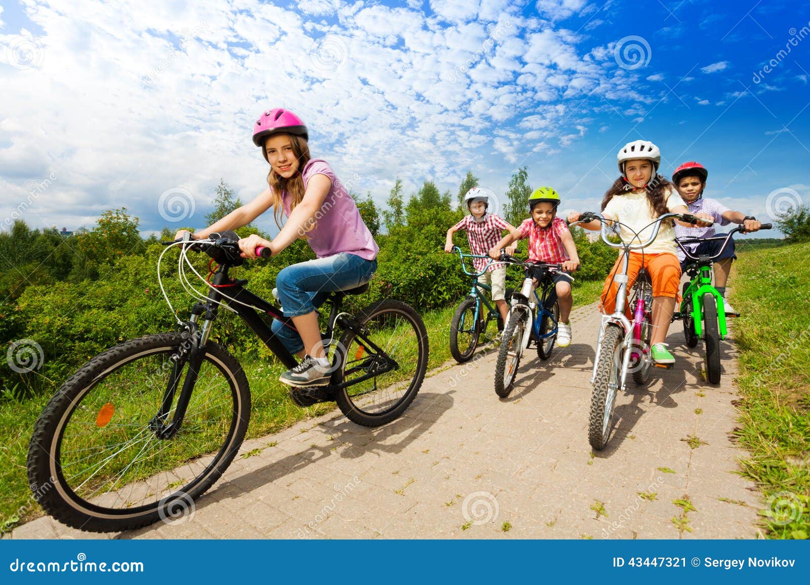 Two Girls And Boys In Helmets Ride Bikes Together Stock Photo Image