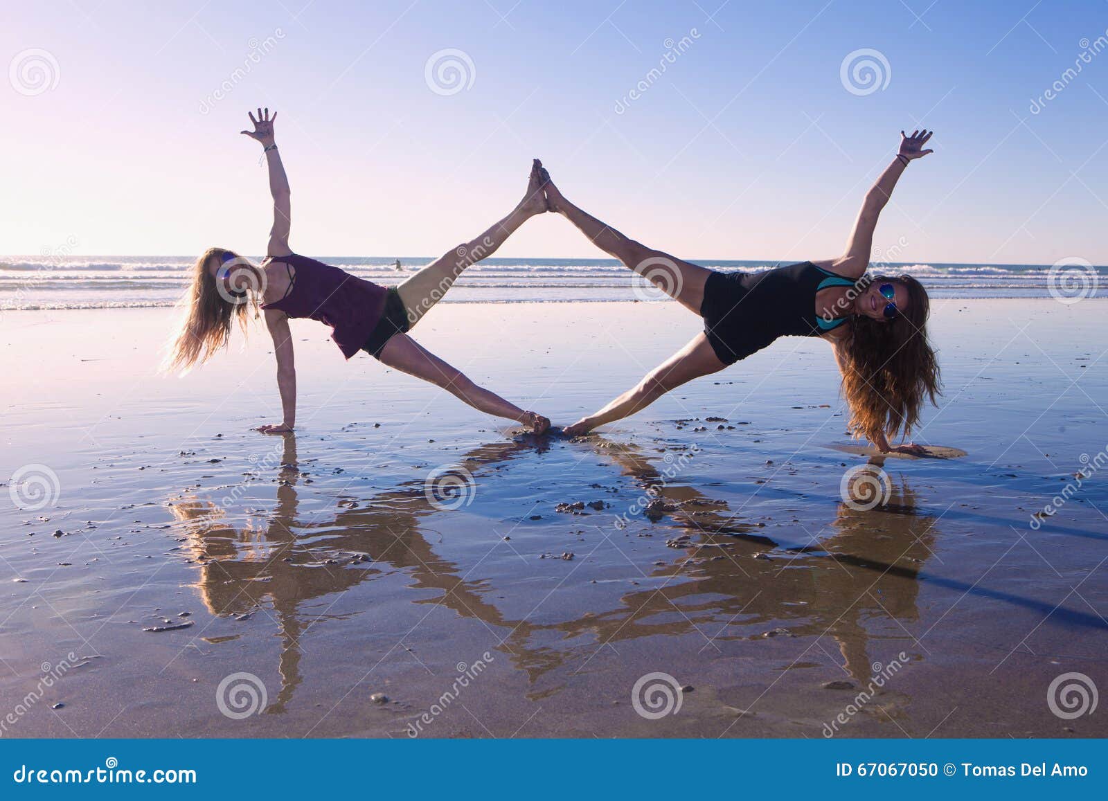 Two women doing yoga on beach in … – License image – 71183451 ❘ lookphotos
