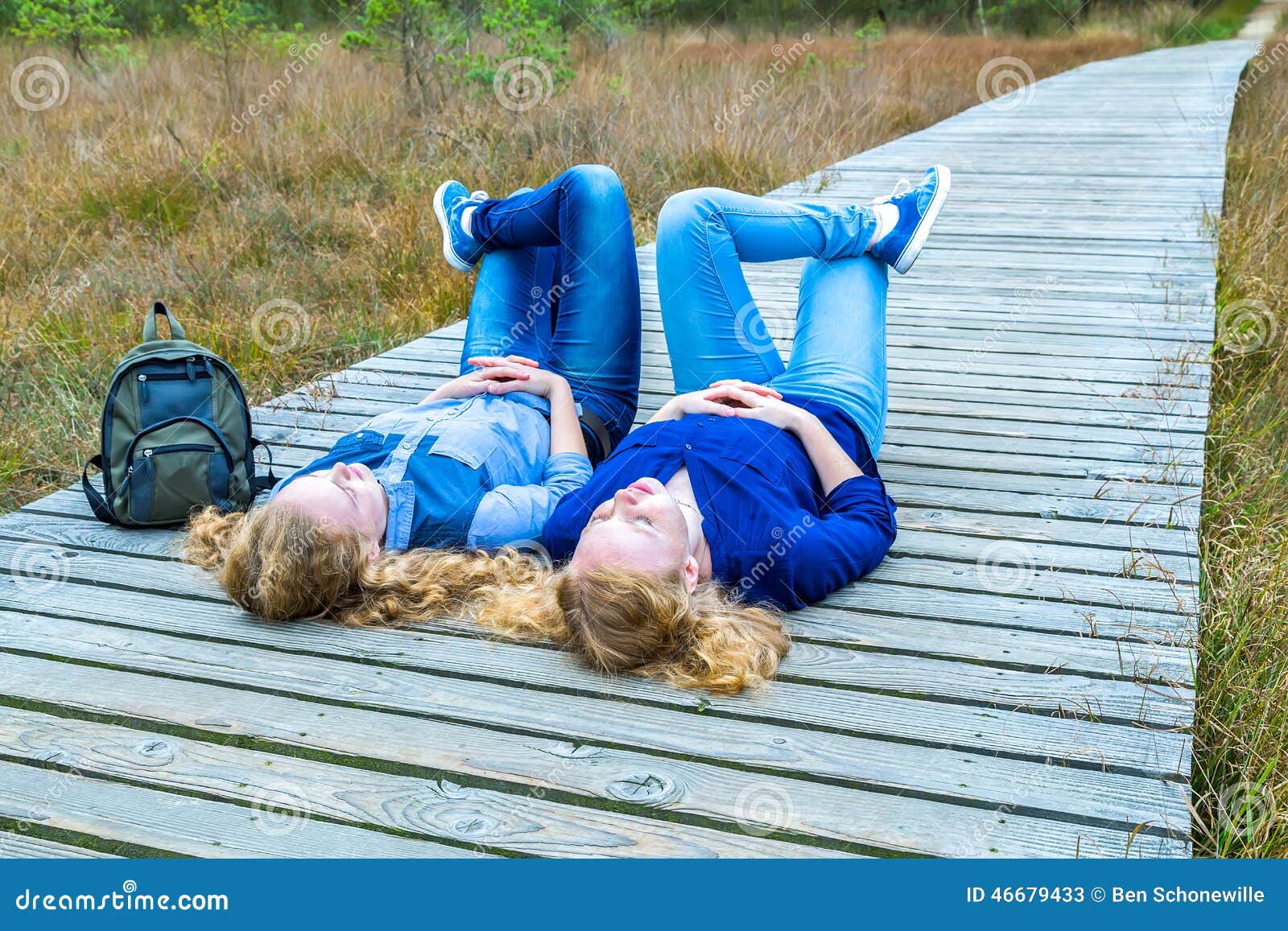 two girls lying on their backs in nature