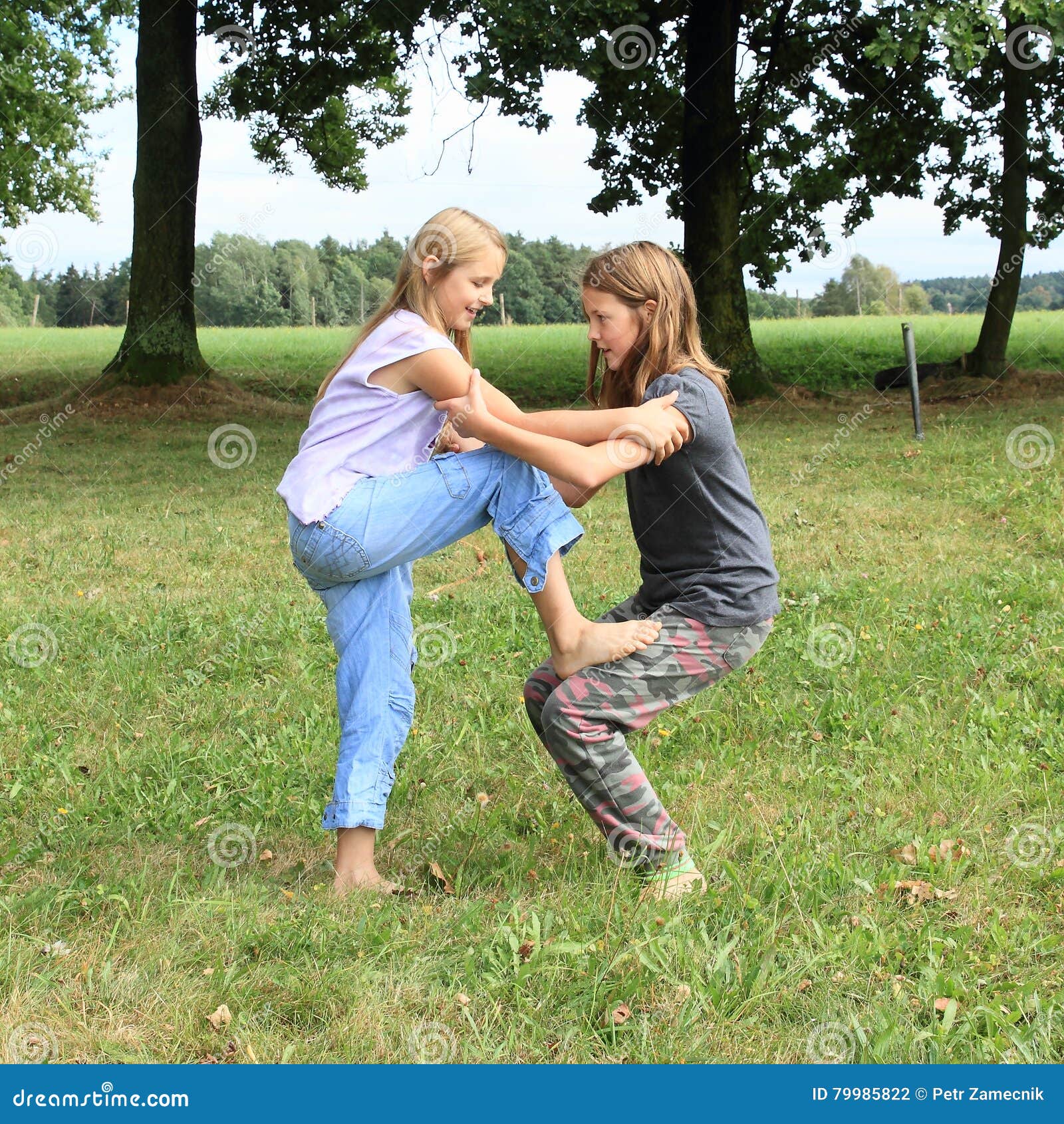 https://thumbs.dreamstime.com/z/two-girls-playing-standing-each-other-little-smiling-barefoot-kids-exercising-one-thigh-one-green-grass-getting-to-yoga-79985822.jpg