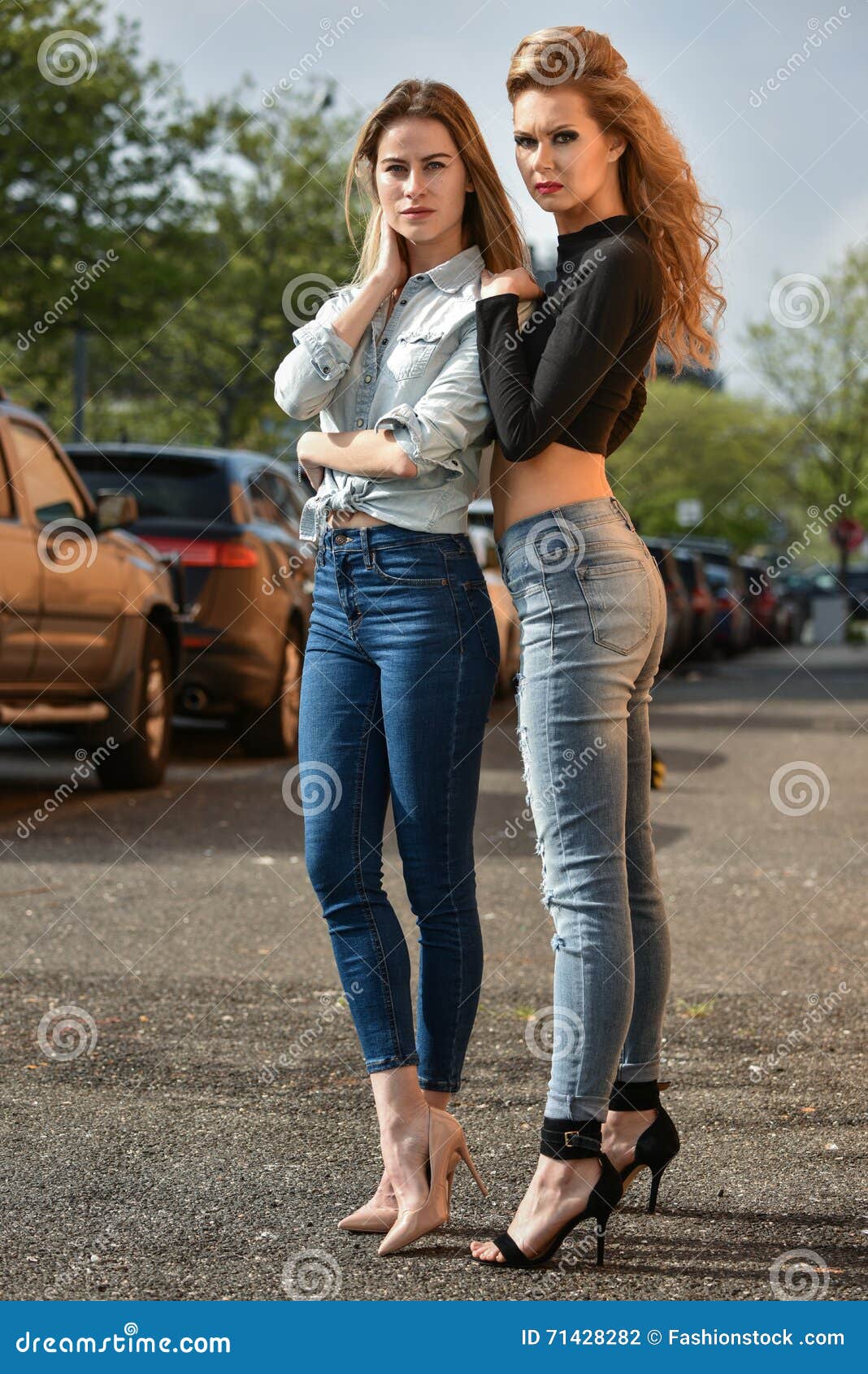 Two young women in formal dress posing barefoot in front of a white wall,  having good time Stock Photo - Alamy