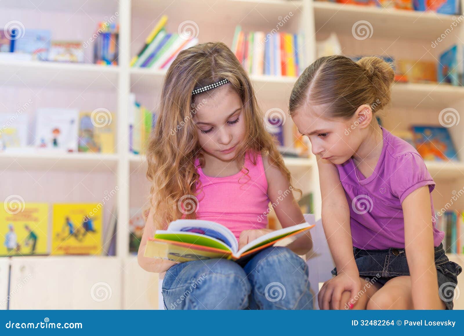 two girls are reading an interesting book