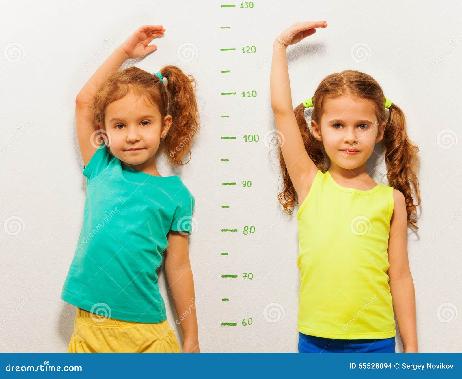 Two Girls Show Height on Wall Scale at Home Stock Photo - Image of