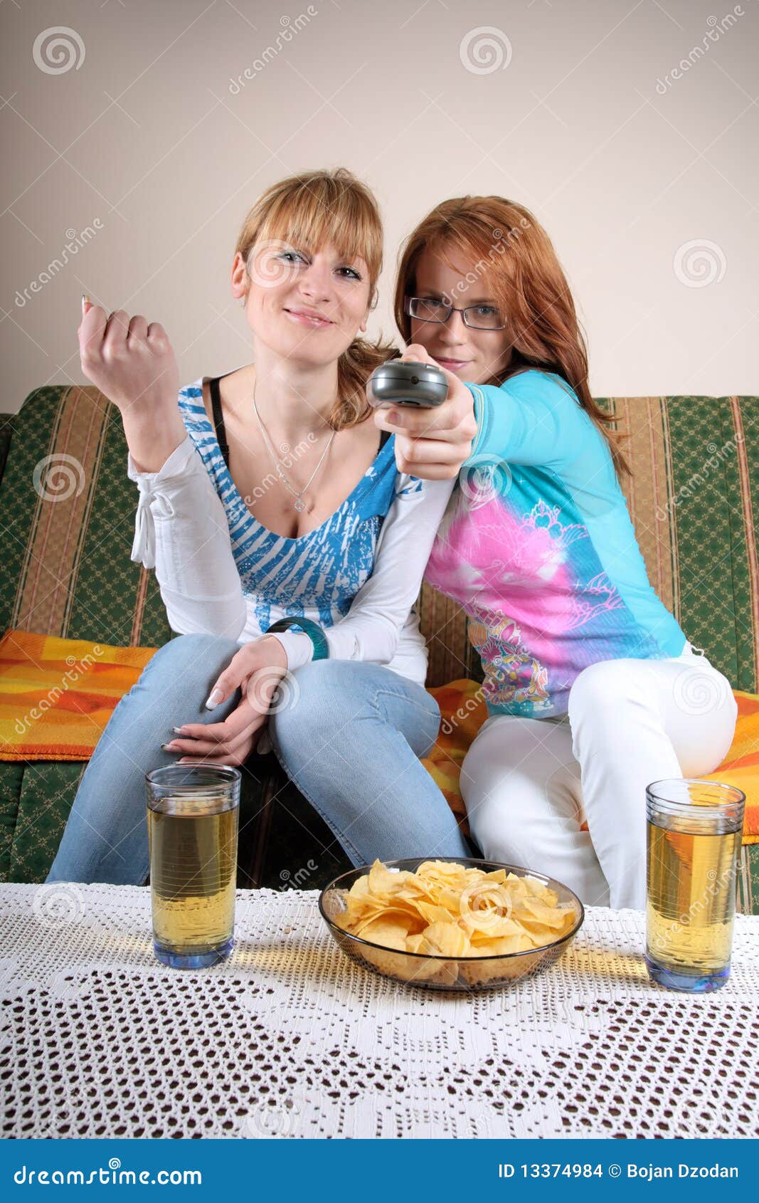Two Girls Watching Shocked Content On Tablet Device On Beige Stock Image