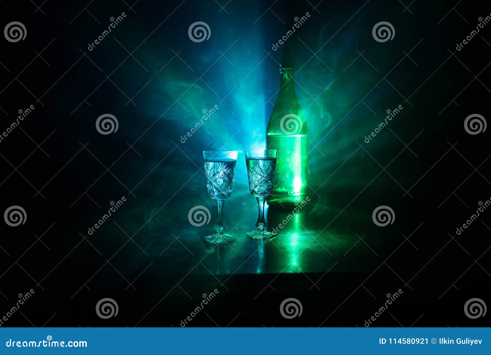 two glasses of vodka with bottle on dark foggy club style background with glowing lights (laser, stobe) multi colored. club drinks