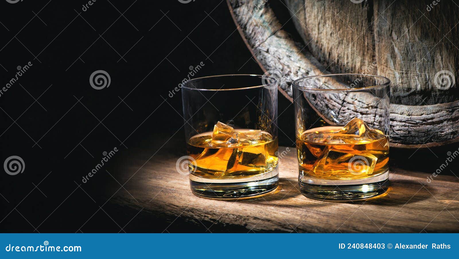 Two Glasses of Whiskey with Ice Cubes in Front of Old Barrel Stock